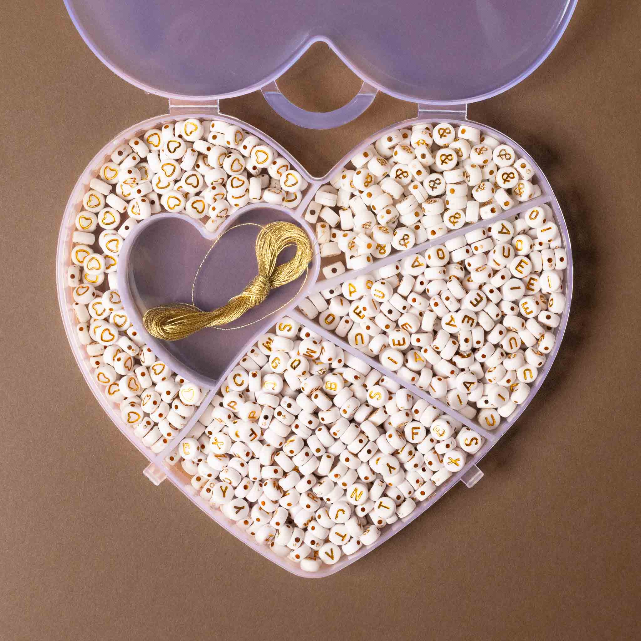 Heart-shaped container filled with letter beads on a brown background
