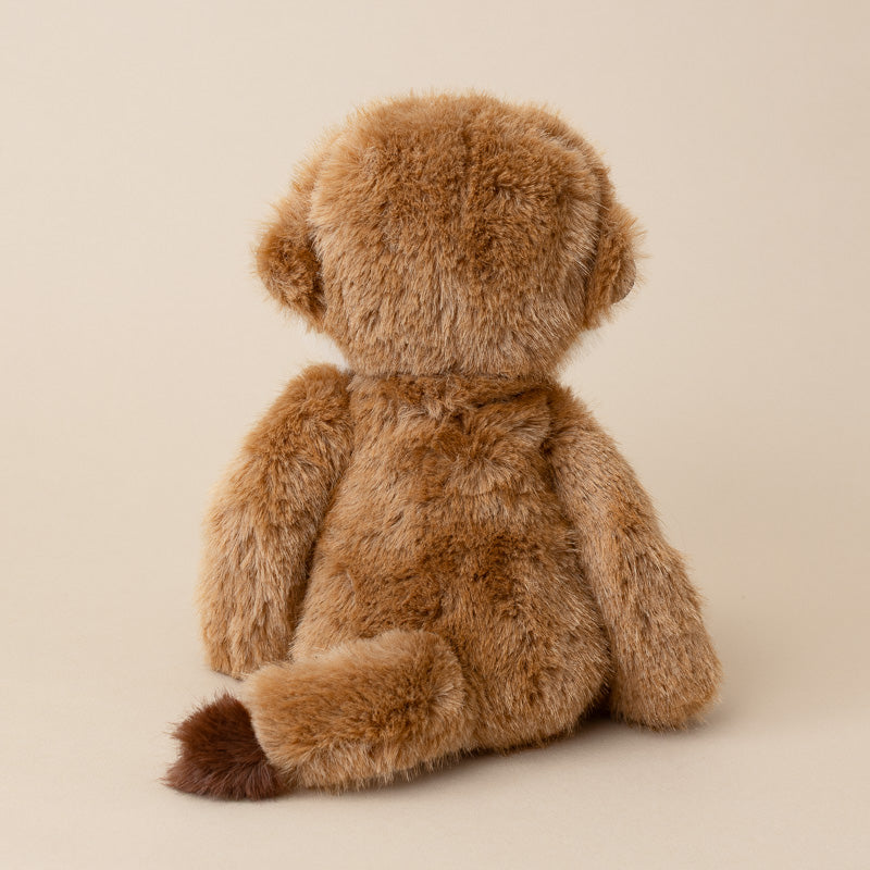 A brown plush monkey toy shown from the back, sitting against a solid light beige background.