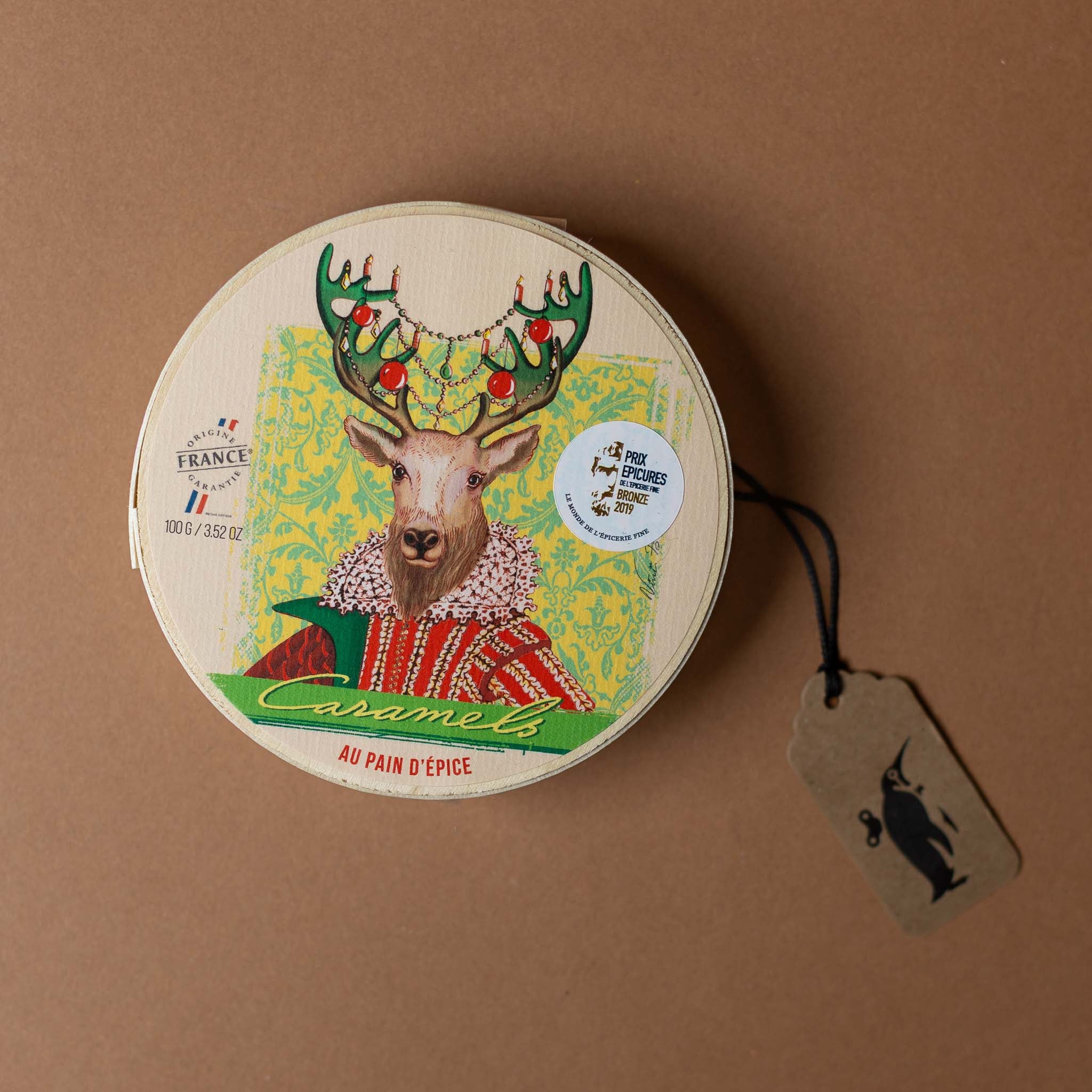 mon-pari-gourmand-caramels-gingerbread-with-chip-wood-box Round product packaging with a deer illustration on a brown background