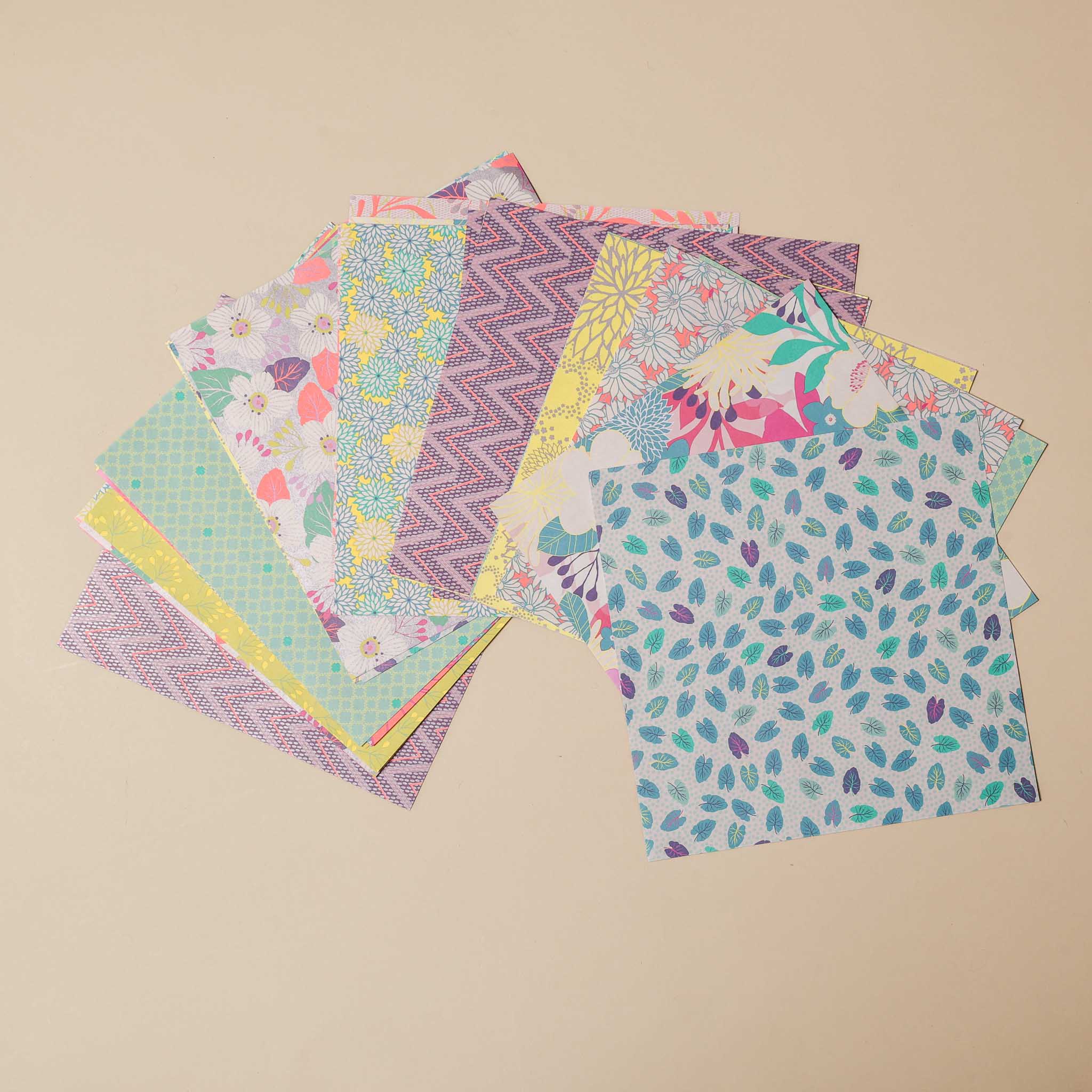 mon-petit-origami-kit-violet Stack of colorful patterned paper sheets on a beige background
