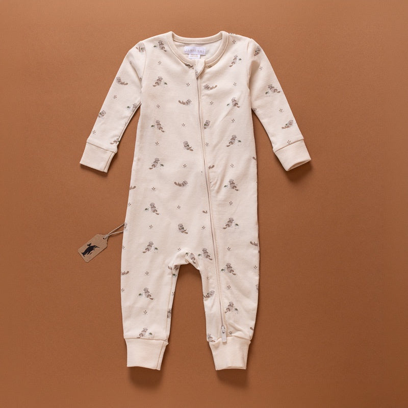 A cream-colored long-sleeve baby footless jumpsuit with a small all-over floral print, laid flat on a warm brown background.