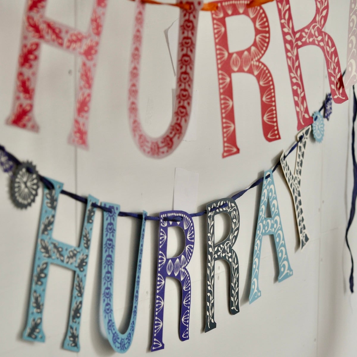 Decorative banner with 'HURRA' letters in red, blue, and purple on a white background
