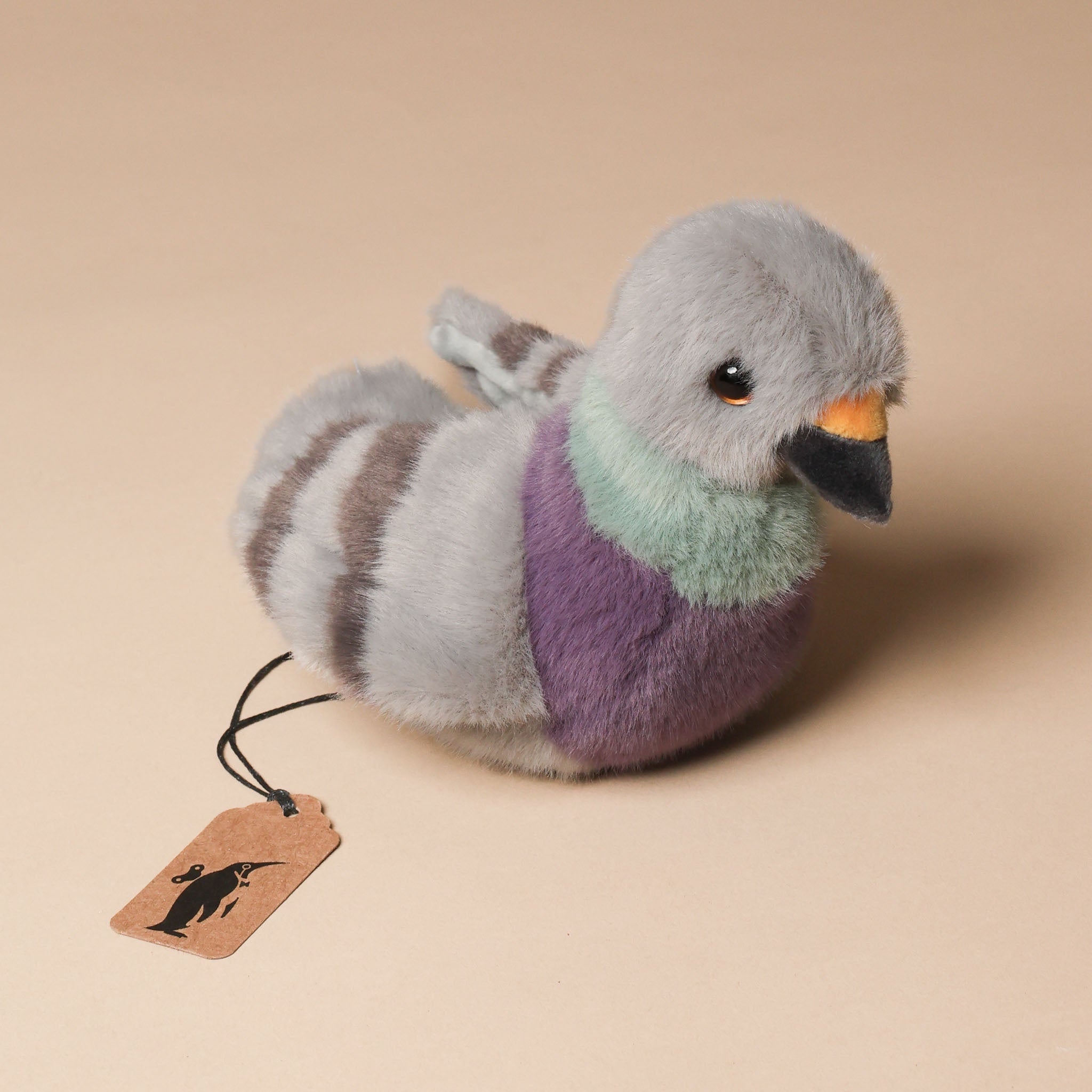 Plush toy pigeon with a tag on a beige background