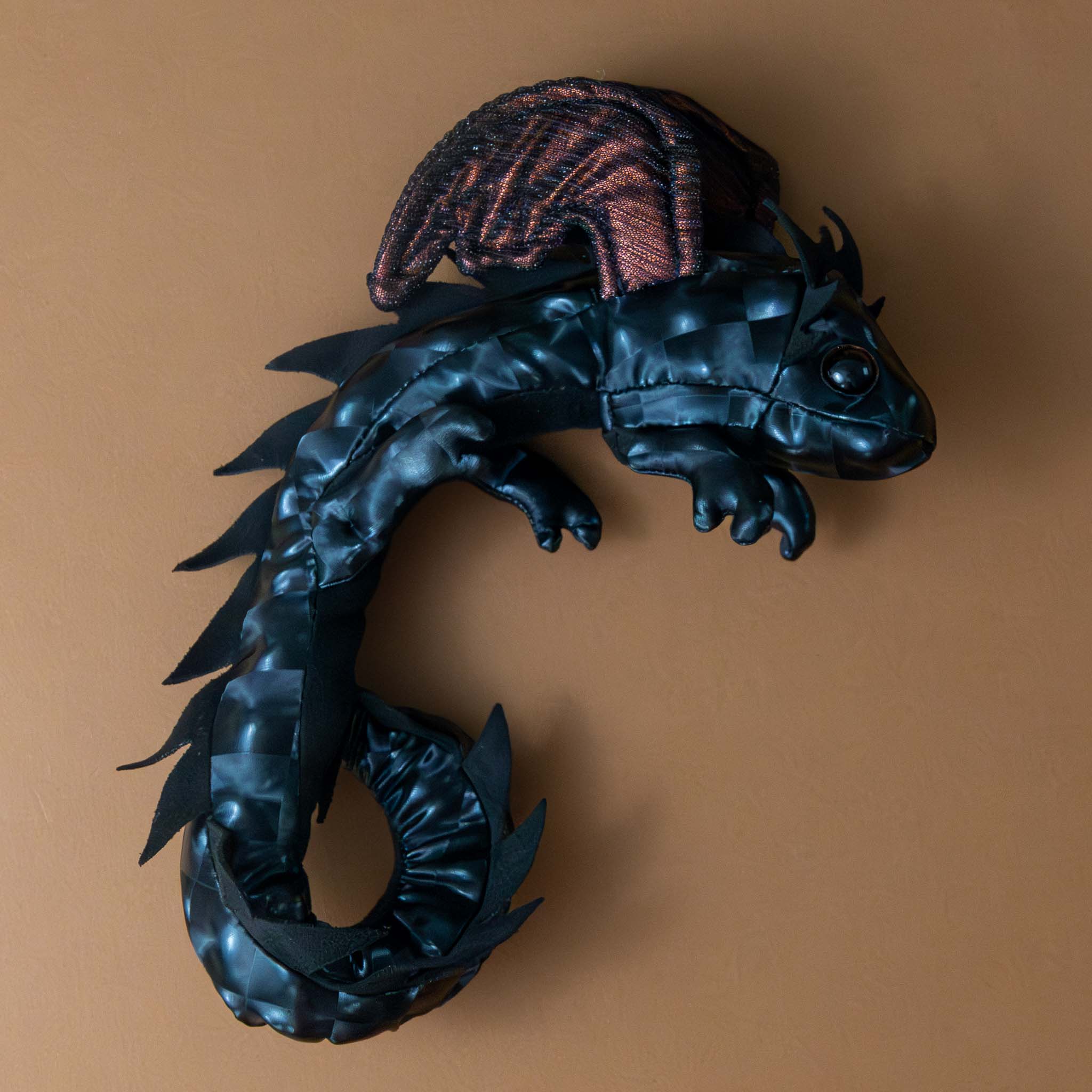 petite-dragon-wristlet-midnight Black dragon-shaped decorative item on a brown background