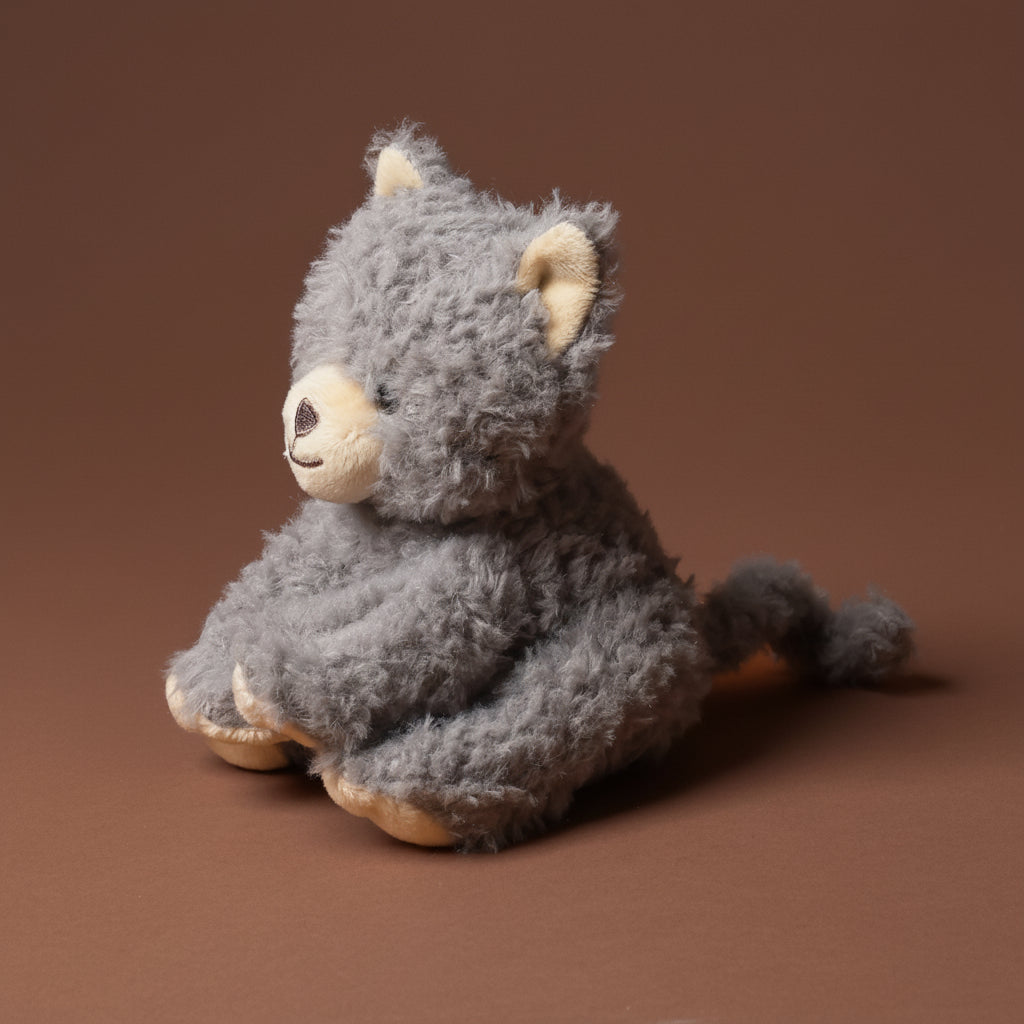 Gray plush petite-romy-the-cat-blueberry toy on a brown background