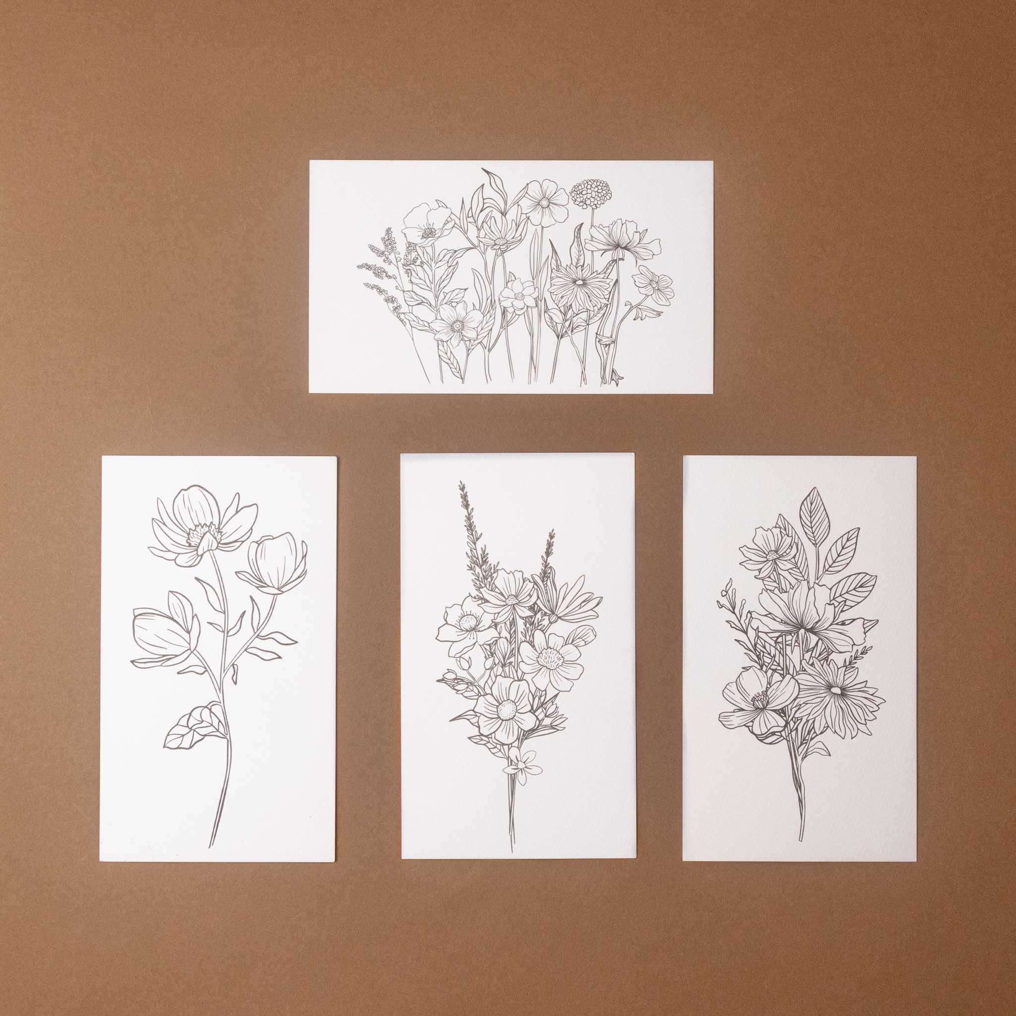 petite-watercolor-painting-kit-wildflower-meadow Set of four floral line drawings on white paper against a brown background