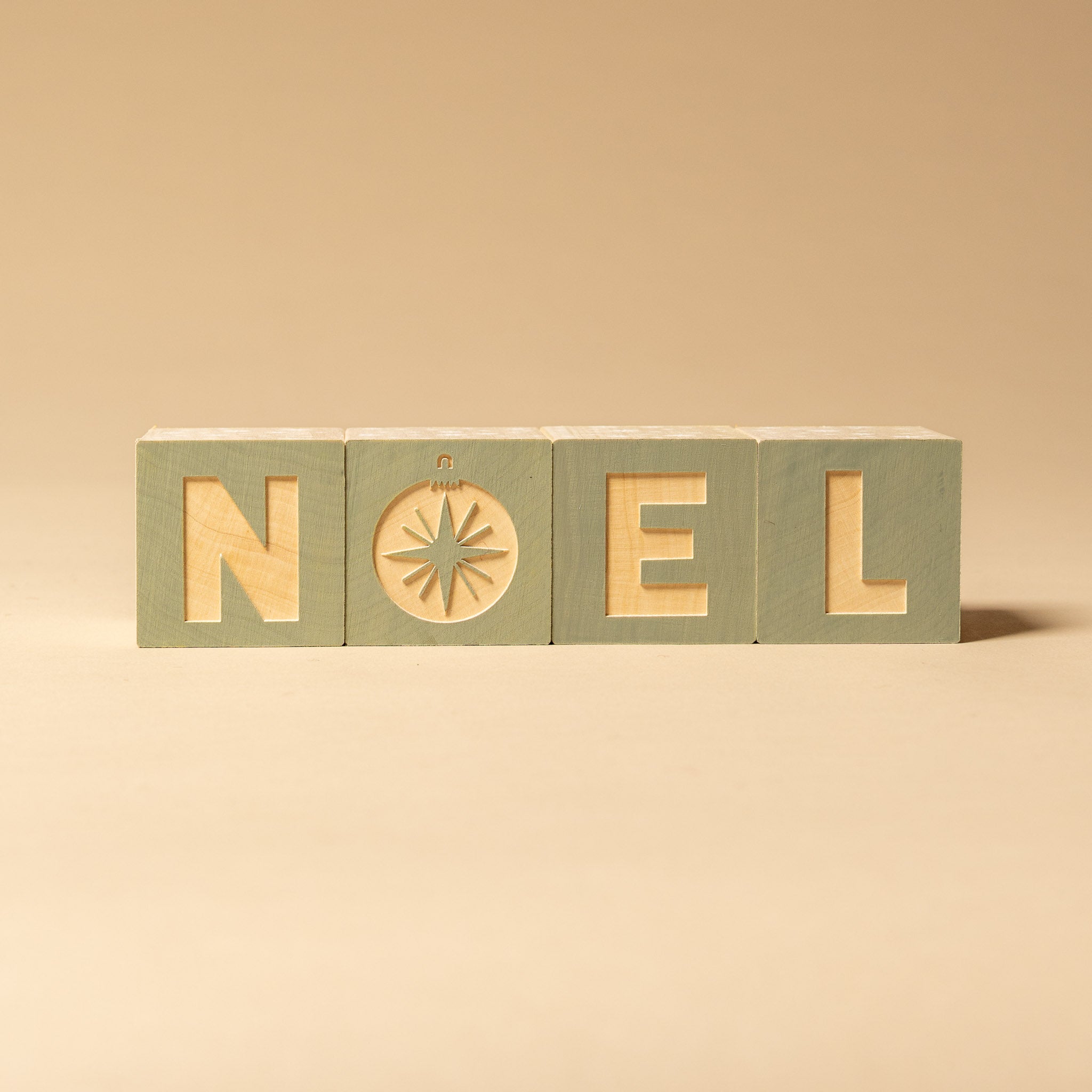 petite-wooden-gifting-block-set-snowglobe Wooden blocks spelling 'NOEL' on a beige background