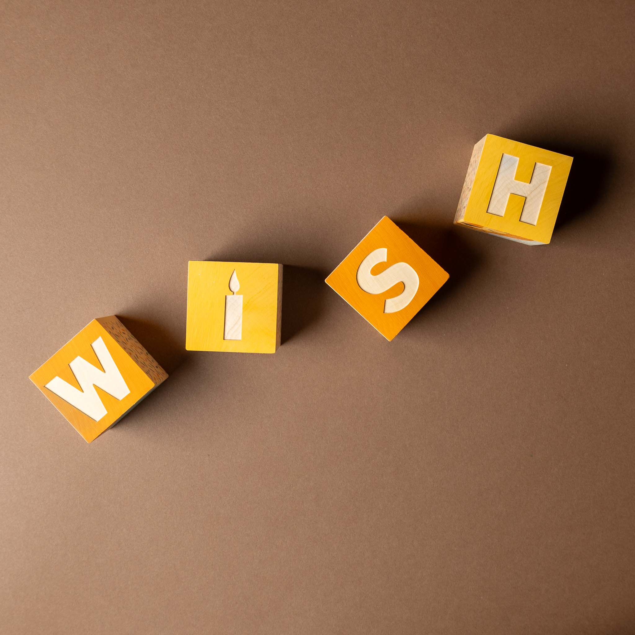 petite-wooden-gifting-block-set-wish Wooden blocks with letters spelling 'WISH' on a brown background