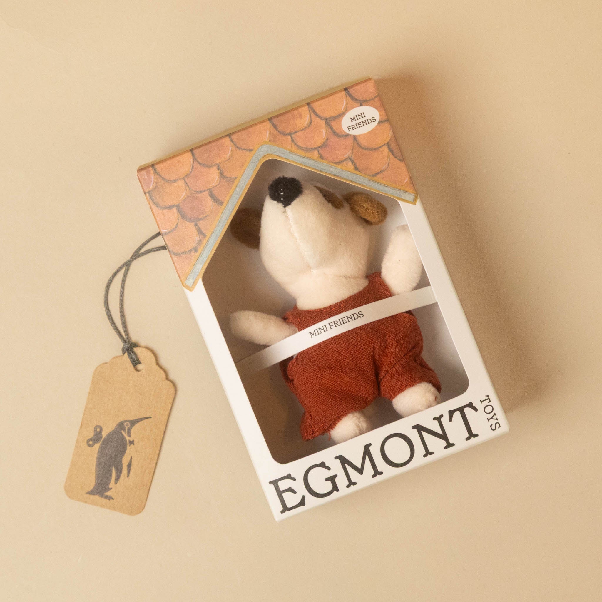 in a house box A small plush dog toy with white and brown fur, wearing a rust-red overall petits-amis-eddie-pup