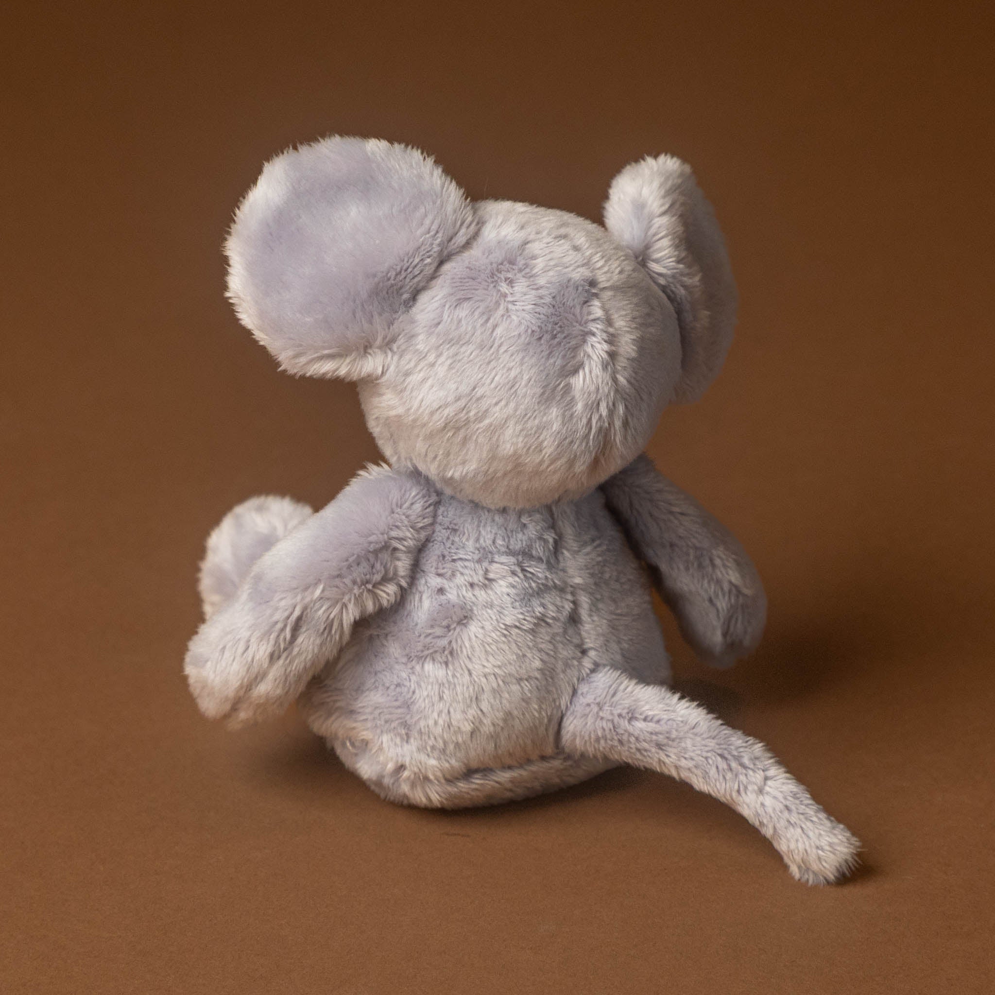 Gray plush pip-the-mouse toy on a brown background