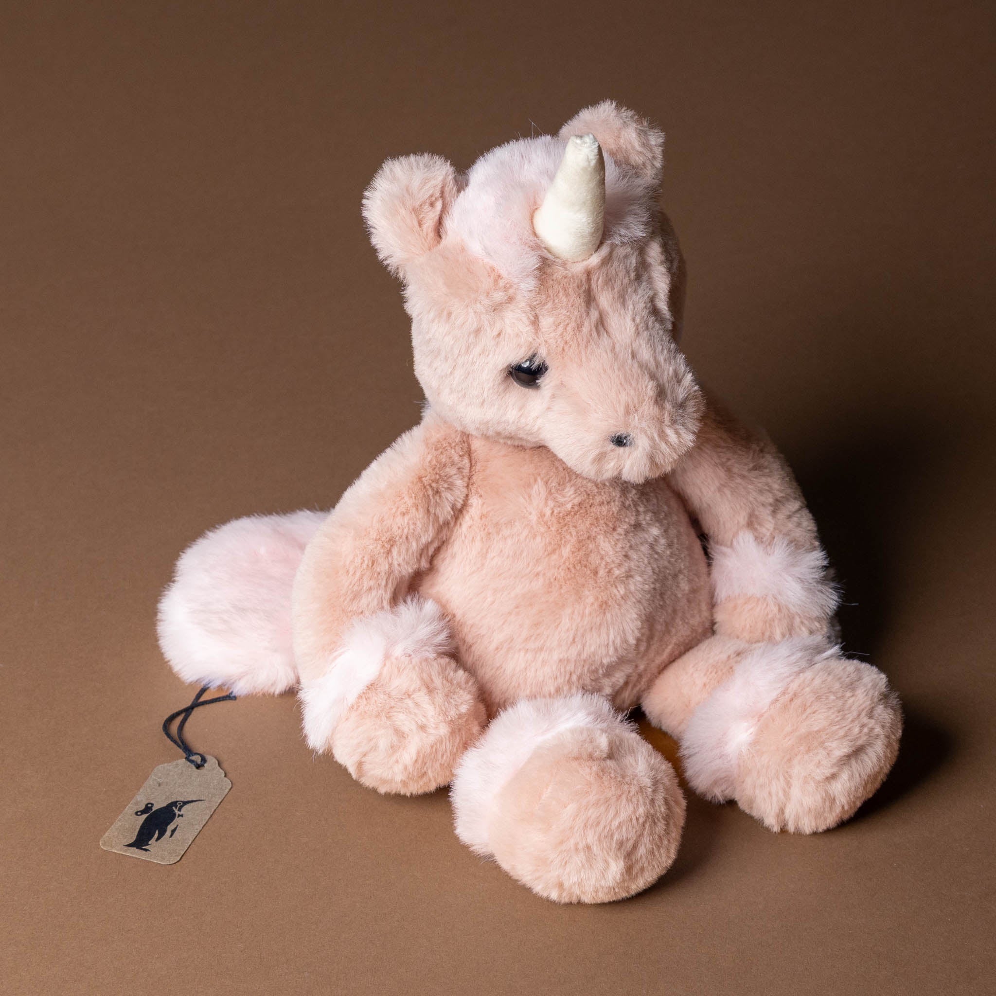 pirouette-the-unicorn Plush unicorn toy with a tag on a brown background