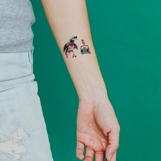 Person's arm with a skatin-city-pigeon-temporary-tattoo-pair on a solid green background