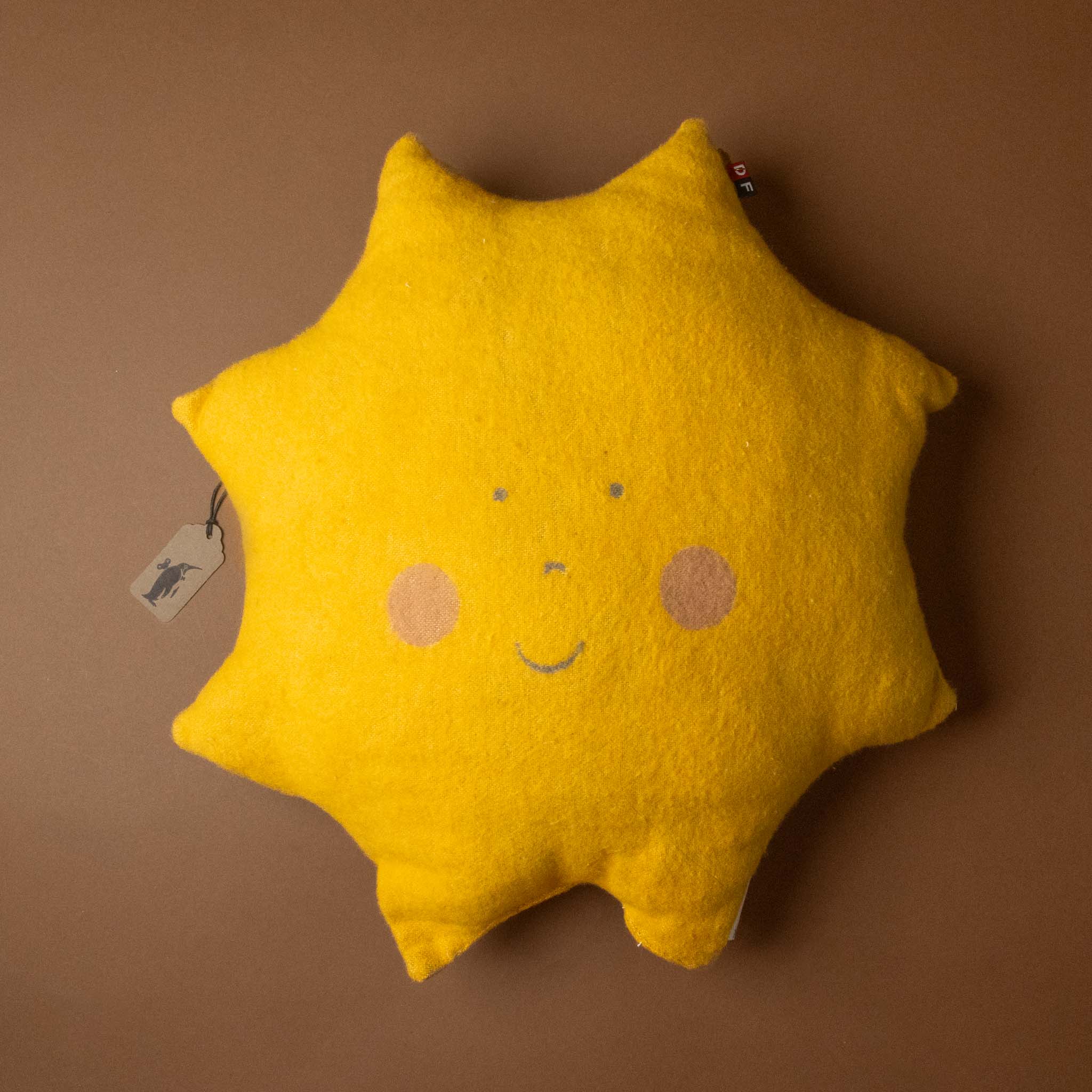 Yellow sun-shaped pillow with a smiley face on a brown background
