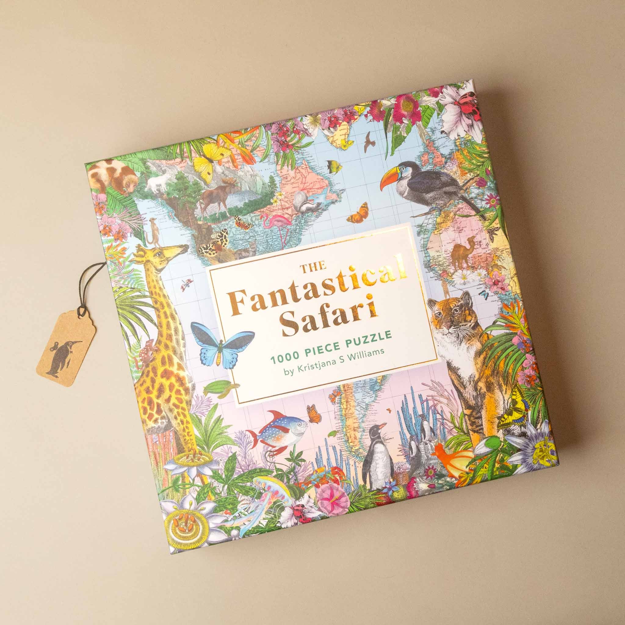 The box of 'The Fantastic Safari' 1000-piece puzzle by Kristjanna S. Williams, featuring a vibrant, detailed safari illustration on the cover, with a small wooden tag attached, set against a solid beige background.