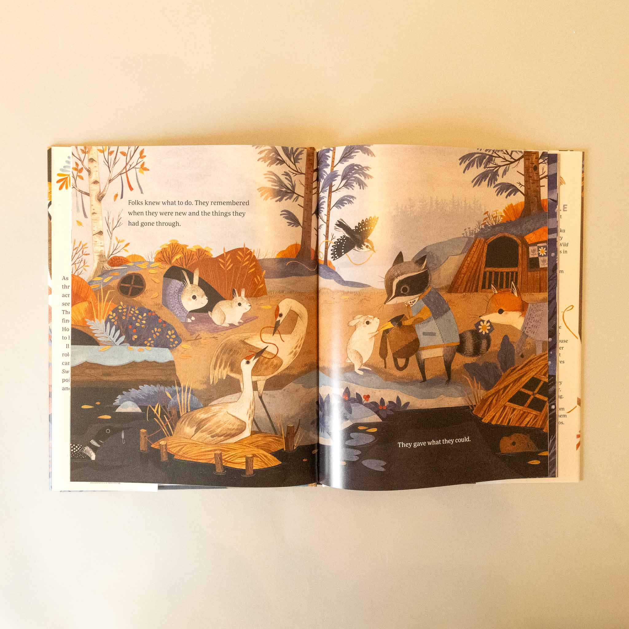 Open the-sweater-a-story-of-community with illustrated pages of animals in a forest setting on a beige background