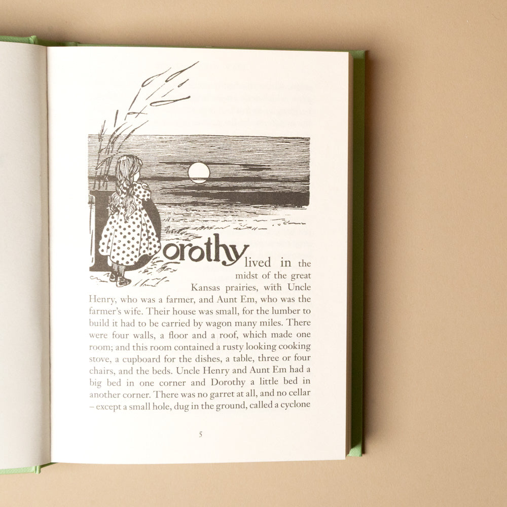 the-wizard-of-oz Open book with a black and white illustration of a girl and text on a beige background