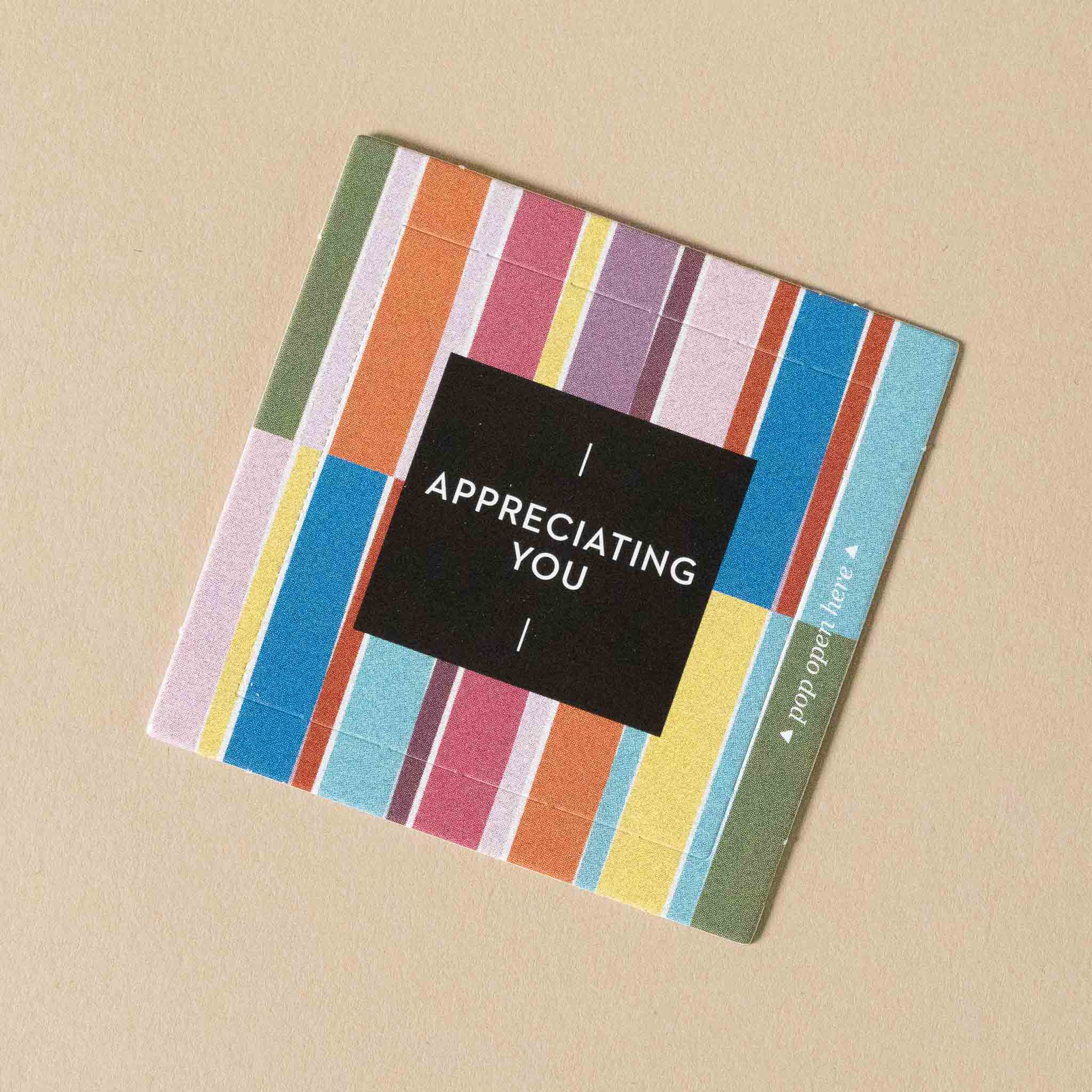 thoughtfulls-pop-open-cards-appreciating-you Colorful striped card with 'I Appreciating You' text on a beige background