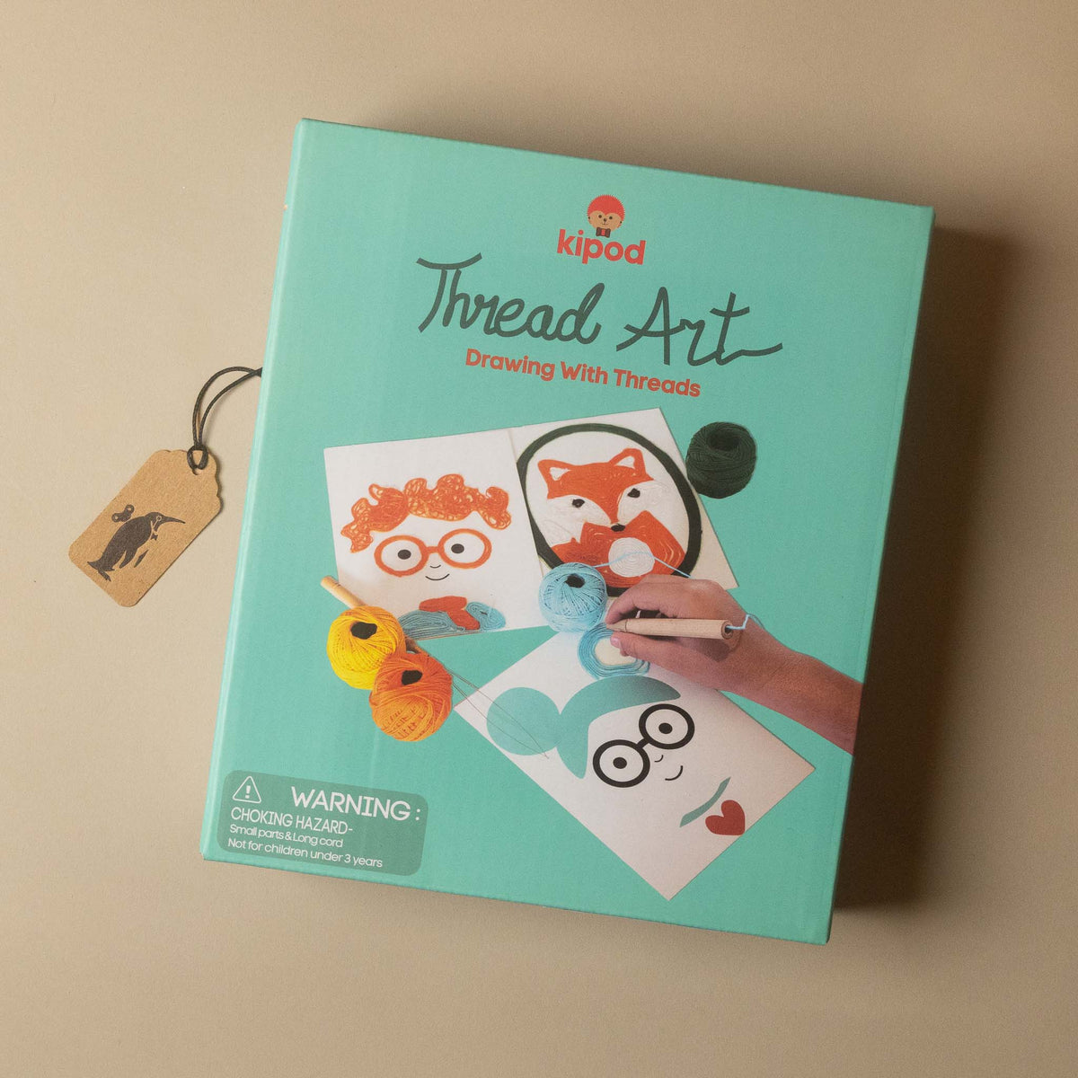thread Art 'Drawing With Threads' kit box in a light teal color, displayed on a beige background with a small wooden brand tag.