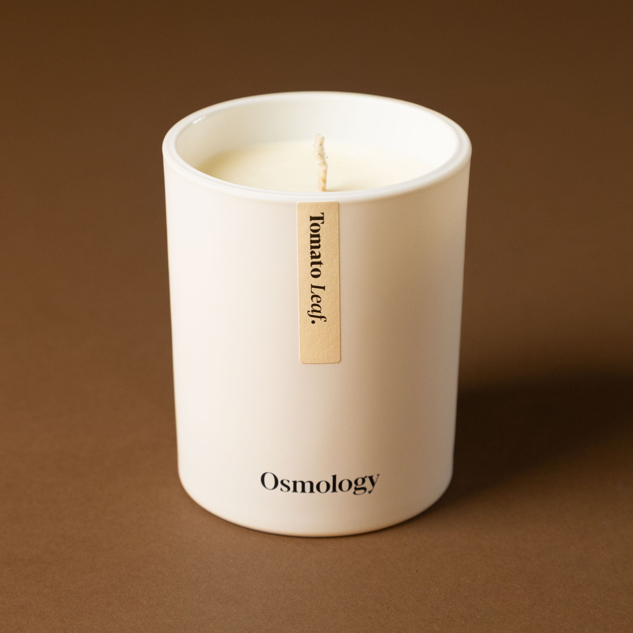 tomato-leaf-candle White candle in a container on a brown background