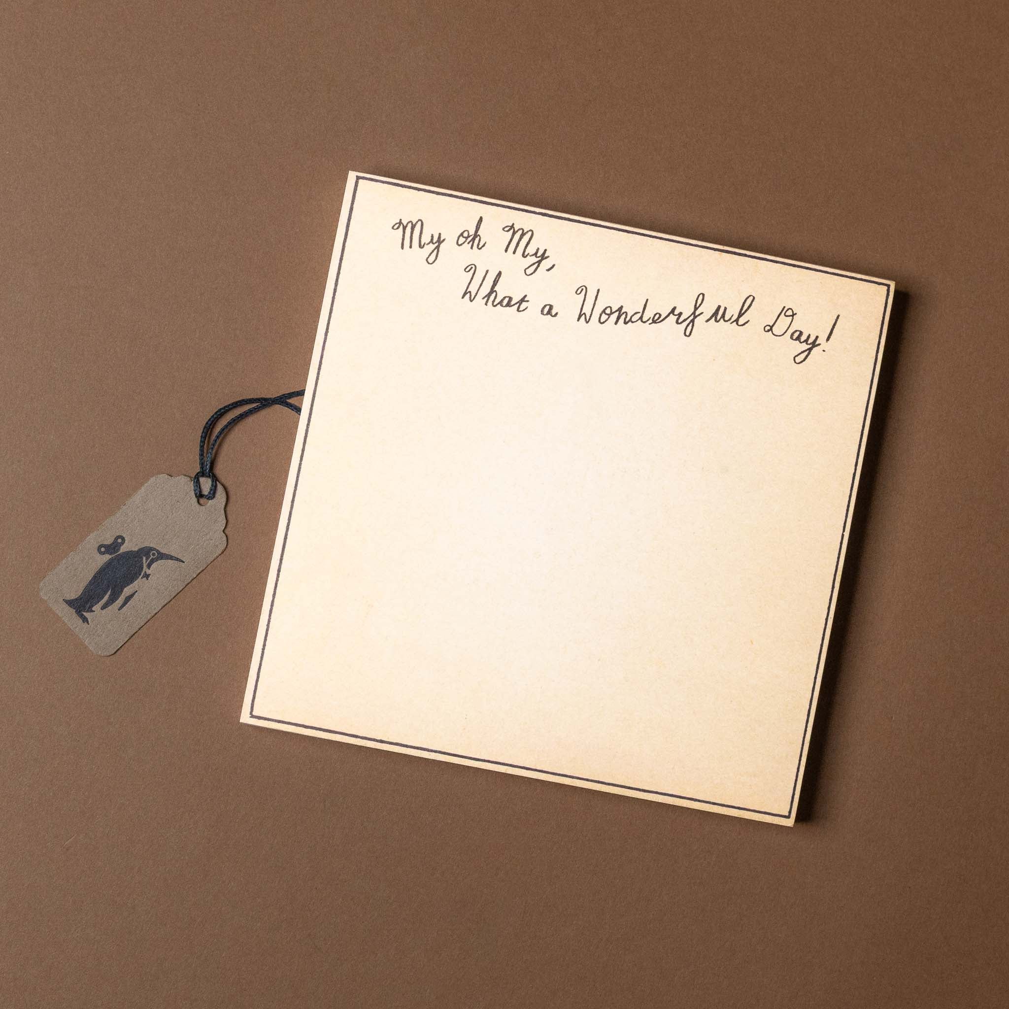 Notebook with 'My oh my, what a wonderful day!' text and a tag on a brown background