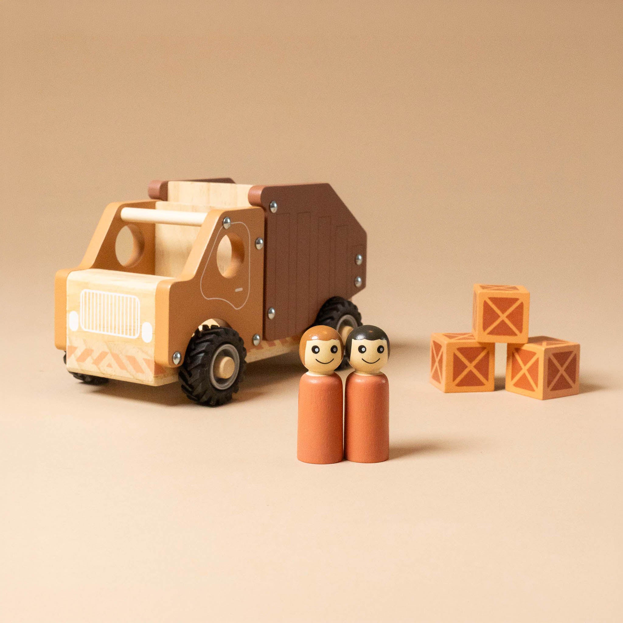 wooden-dump-truck with two figurines and stacked blocks on a beige background