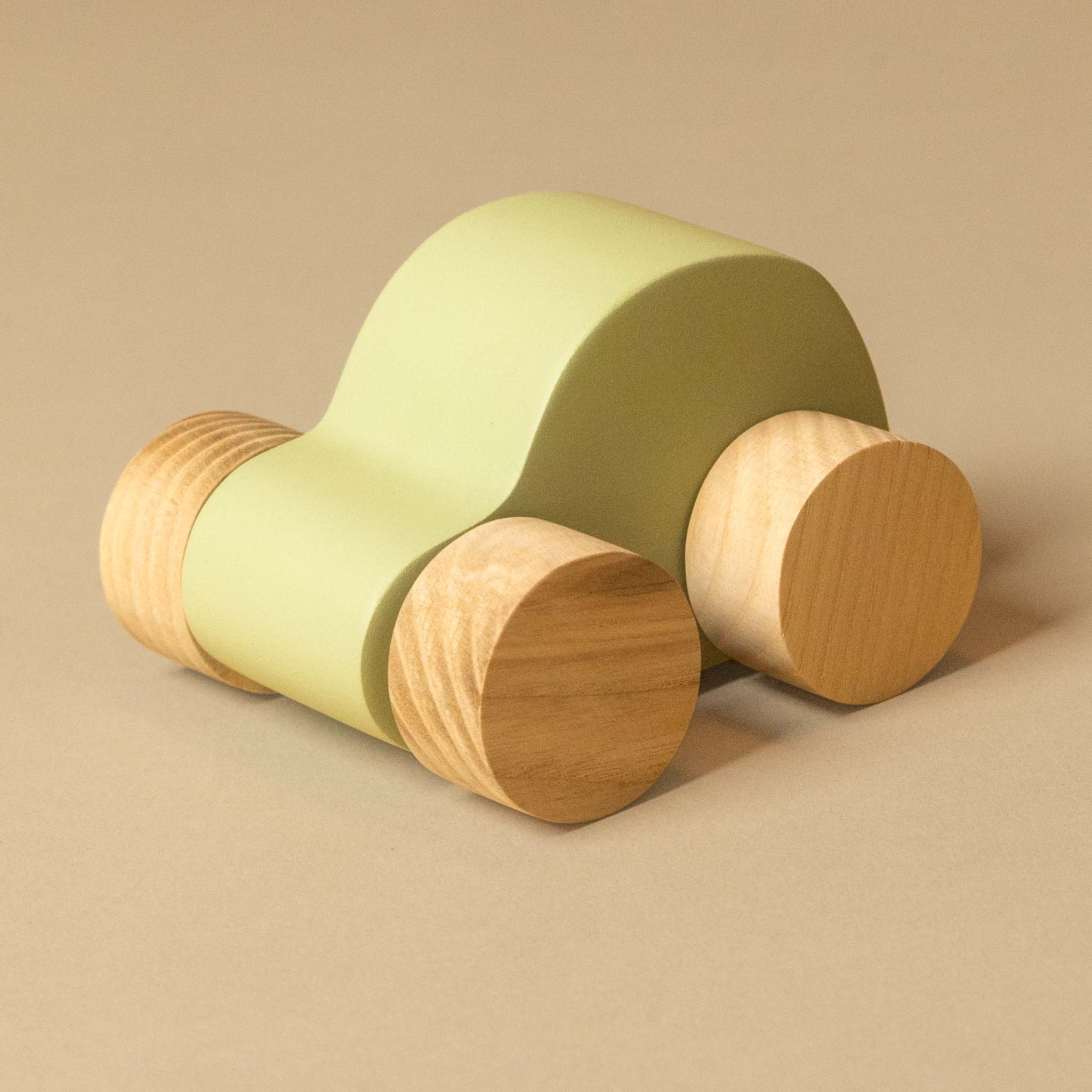 A minimalist wooden toy car with a smooth, curved light green body and natural light wood wheels, set against a solid beige background.