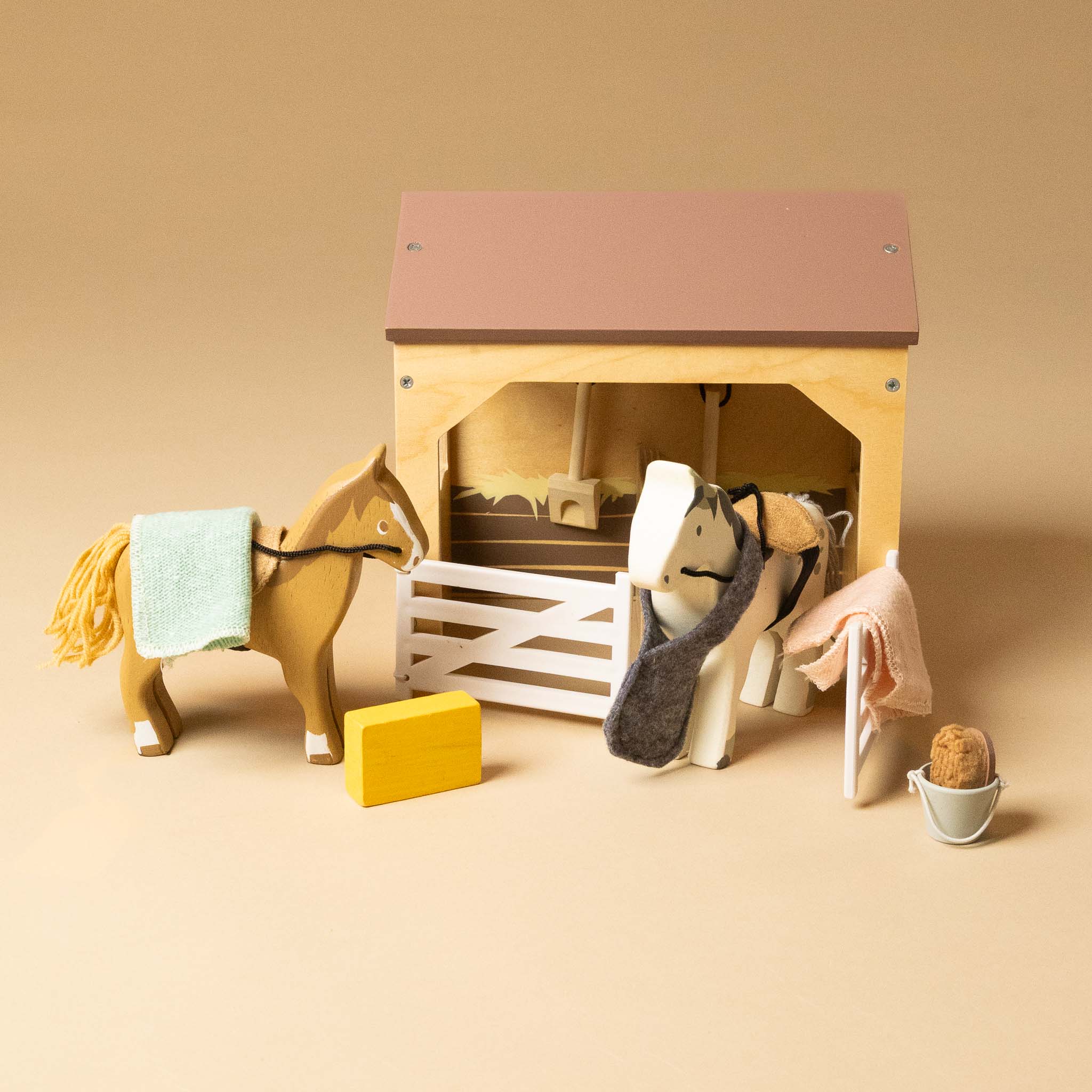 wooden-stable-play-set with two horses and accessories on a beige background