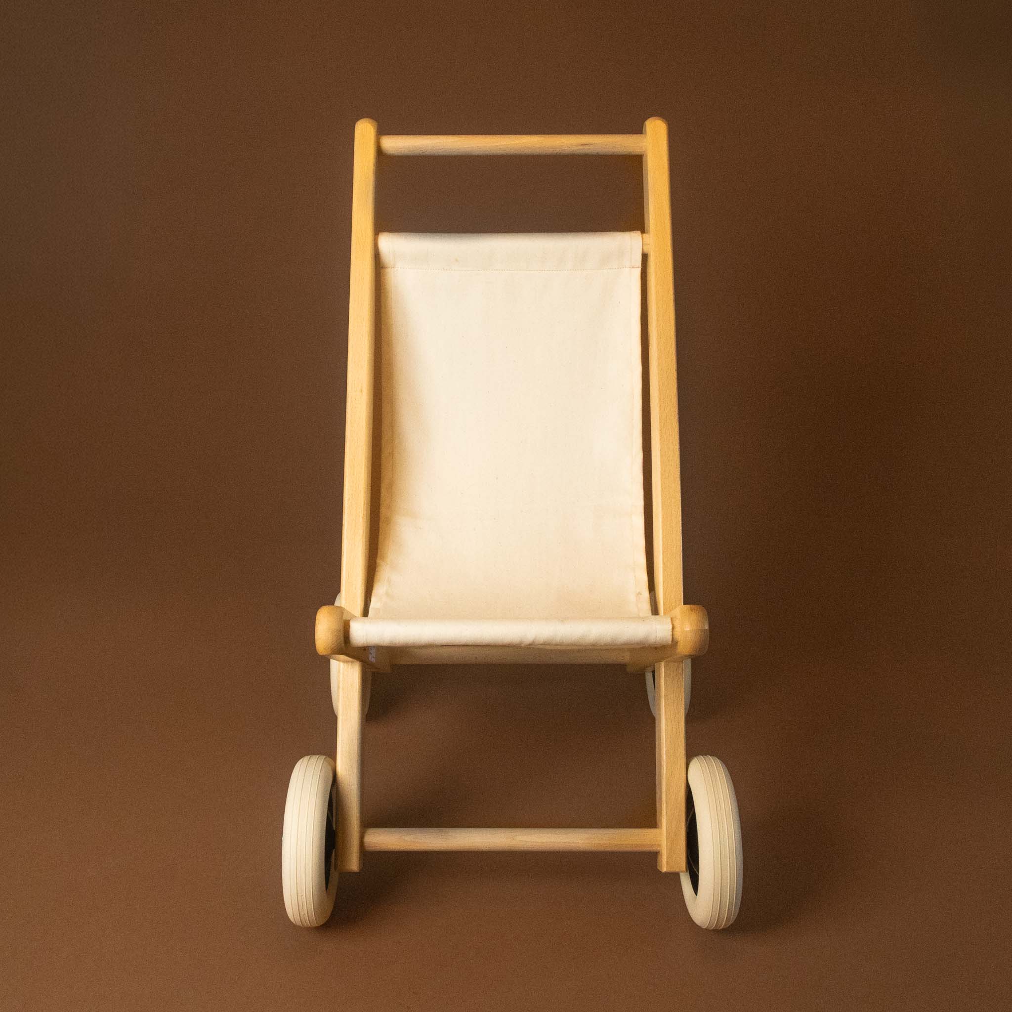 Wooden doll stroller with a beige cushion on a brown background