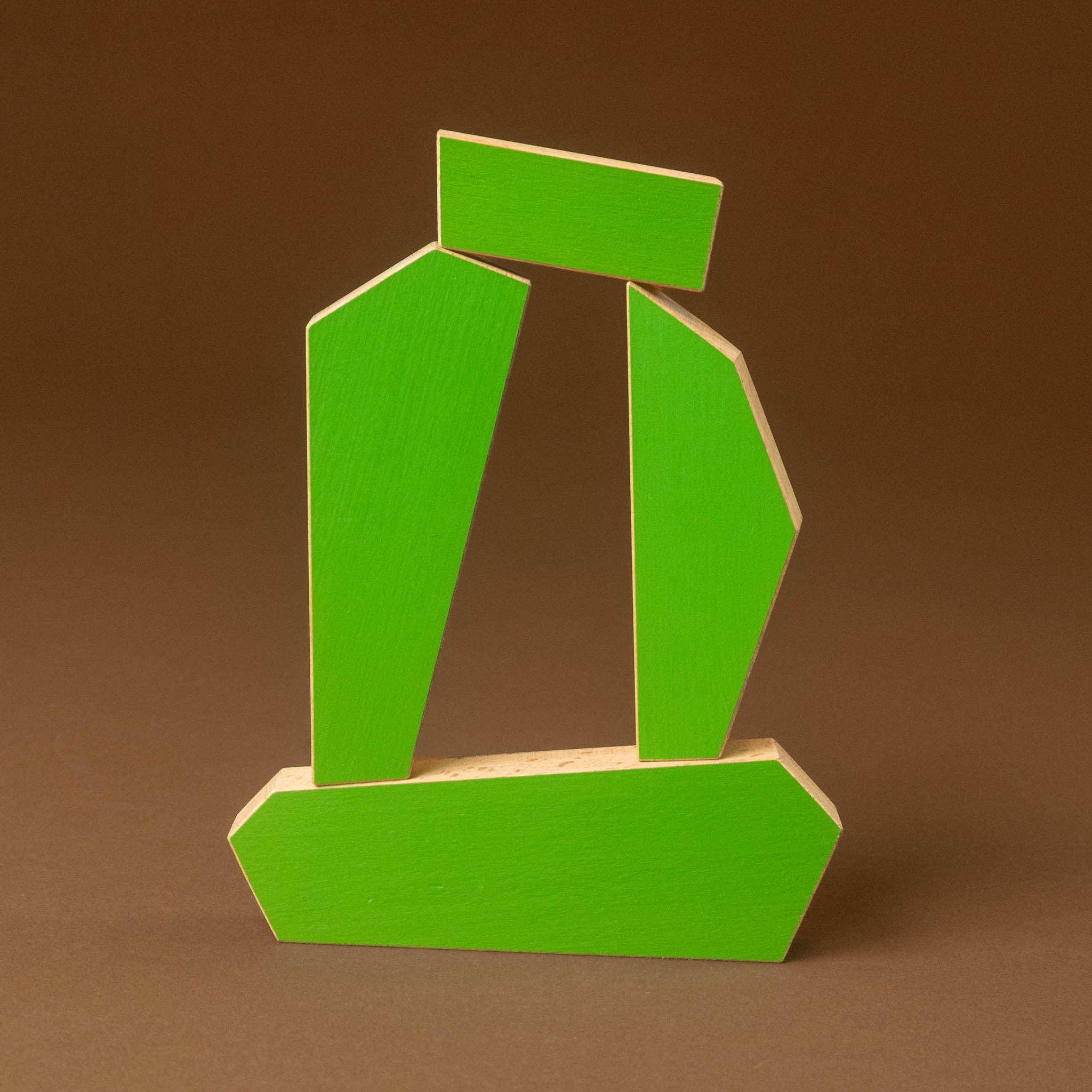 A modern abstract geometric wall sculpture made of bright green painted wood, set against a solid brown background.