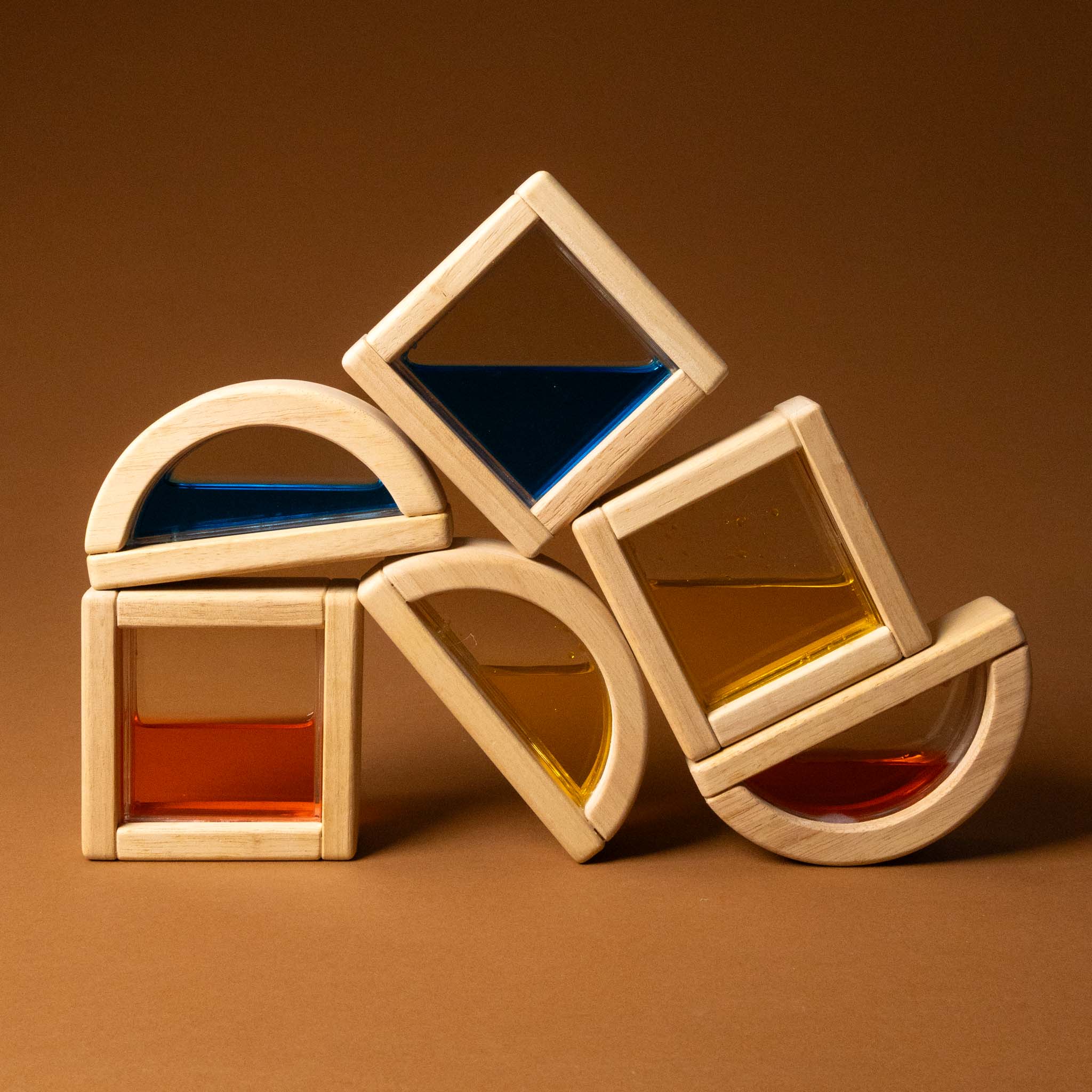 Stack of wooden geometric shapes with colored liquids on a brown background