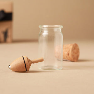 medium-wood-spinning-top-next-to-glass-jar
