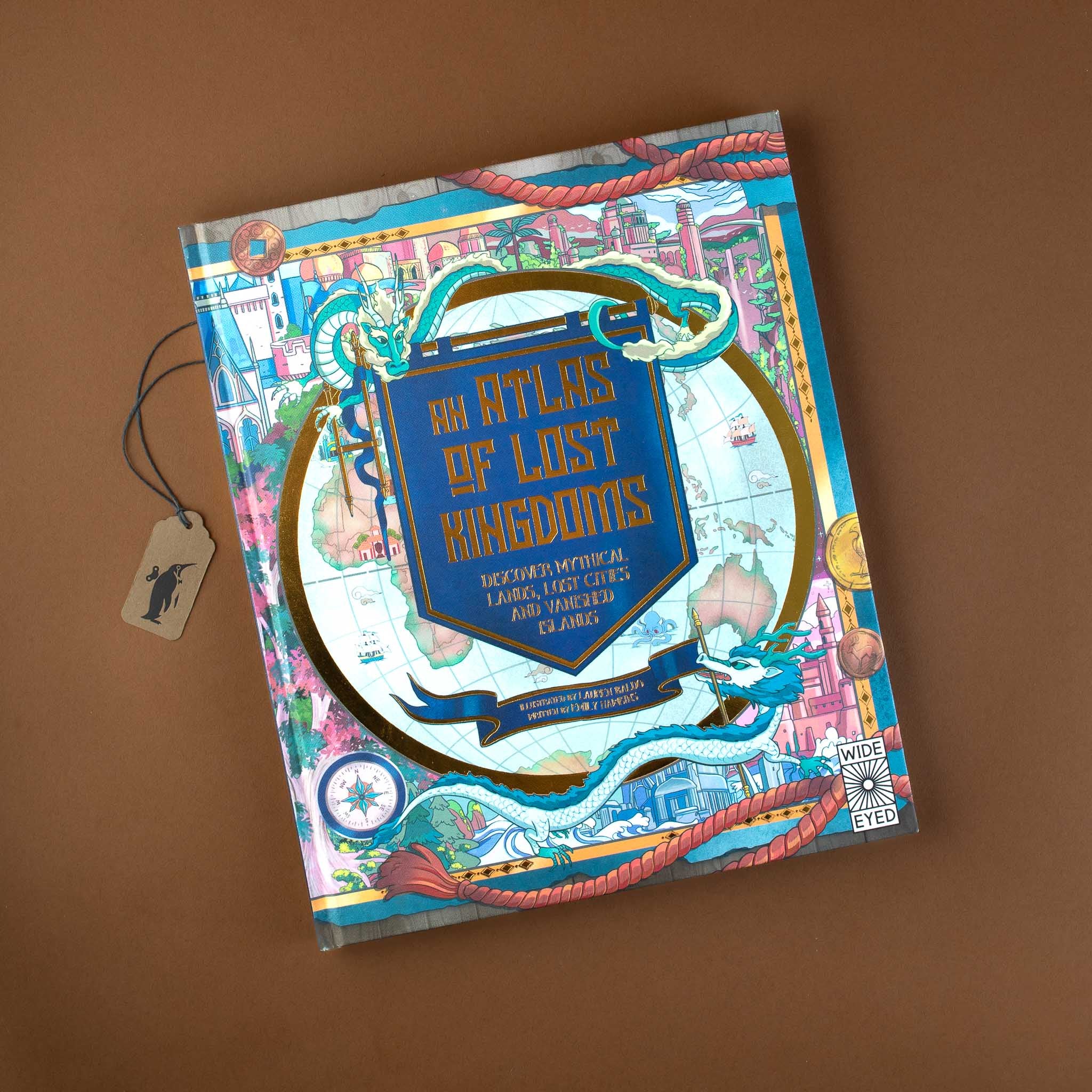 atlas-of-lost-kingdoms-book-in-gold-foil-on-blue-shield-for-front-cover-surrounded-by-dragons-compass-and-kingdom-illustrations