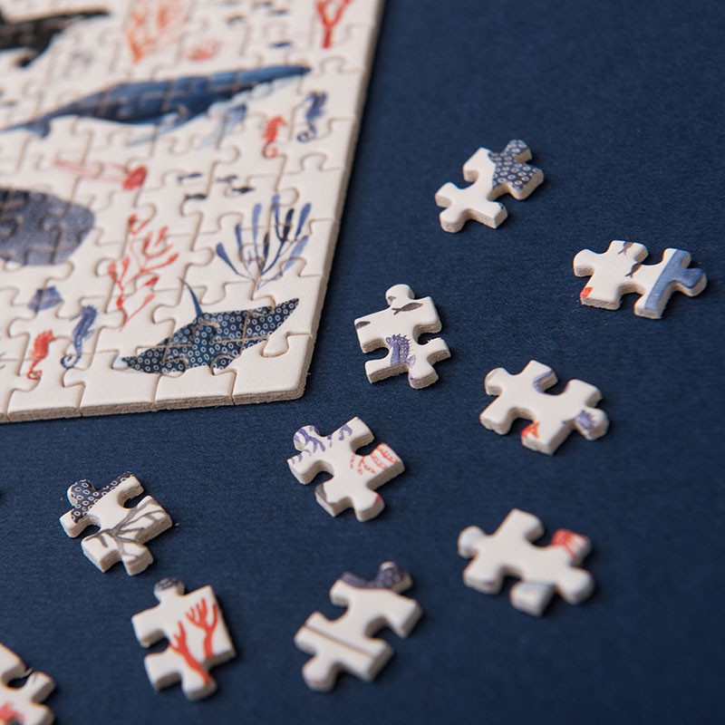 150-piece-micro-puzzle-whales pieces on a blue surface with an incomplete puzzle.