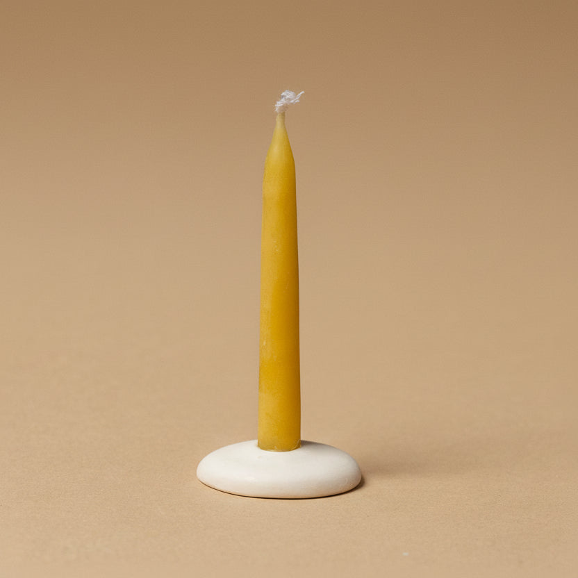 Yellow candle on a white base against a brown background