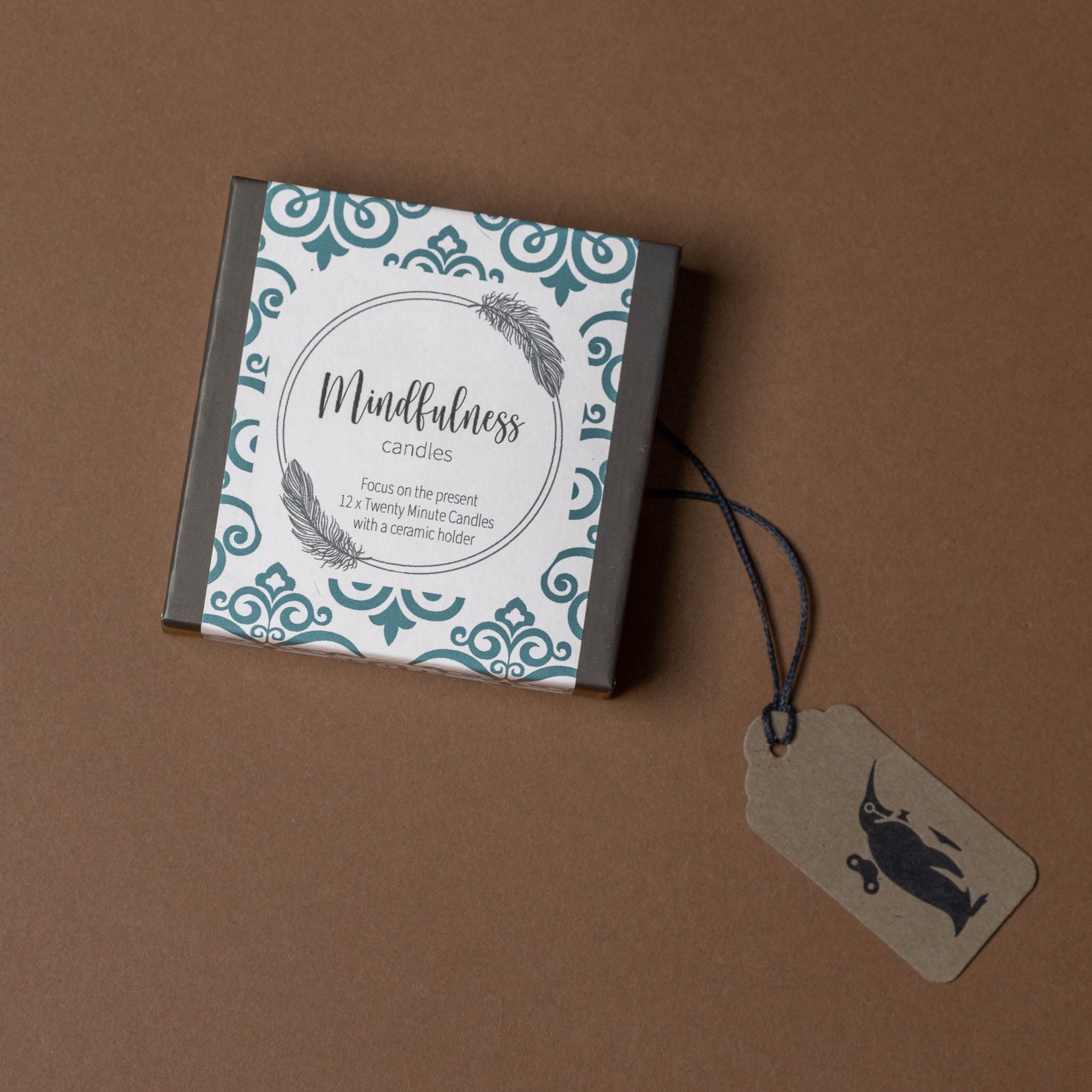 Box of mindfulness candles with decorative label and tag on a brown background