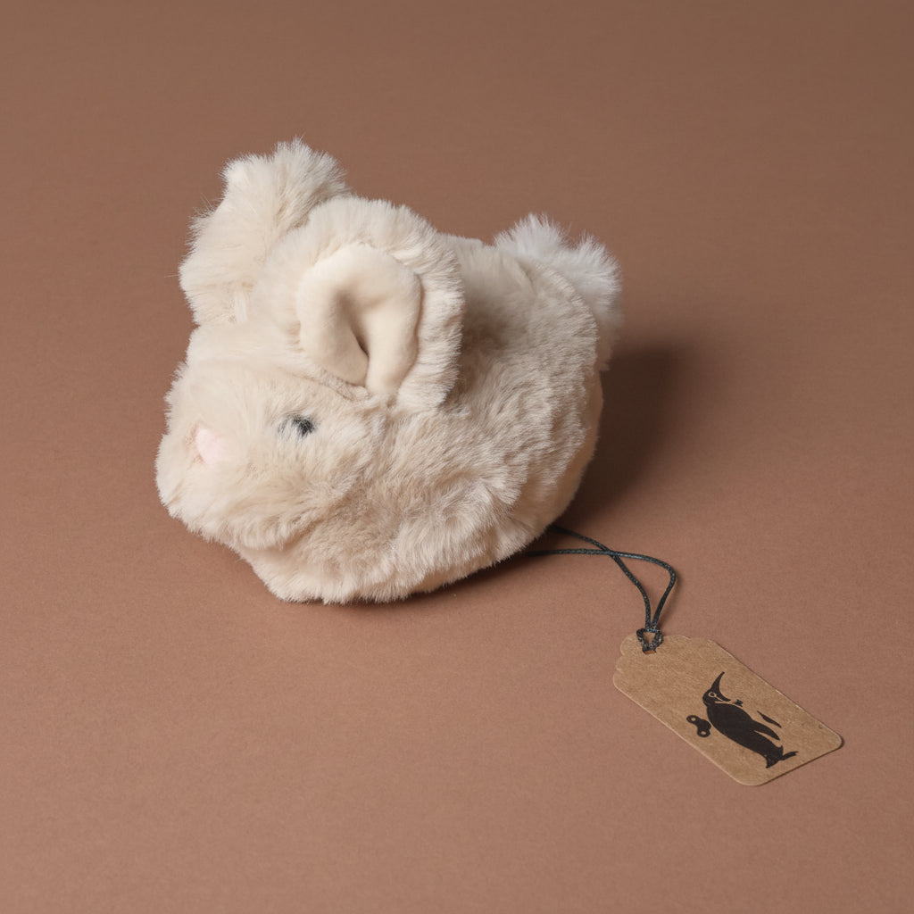 Plush toy Bitty-Bunny-Beige with a tag on a brown background