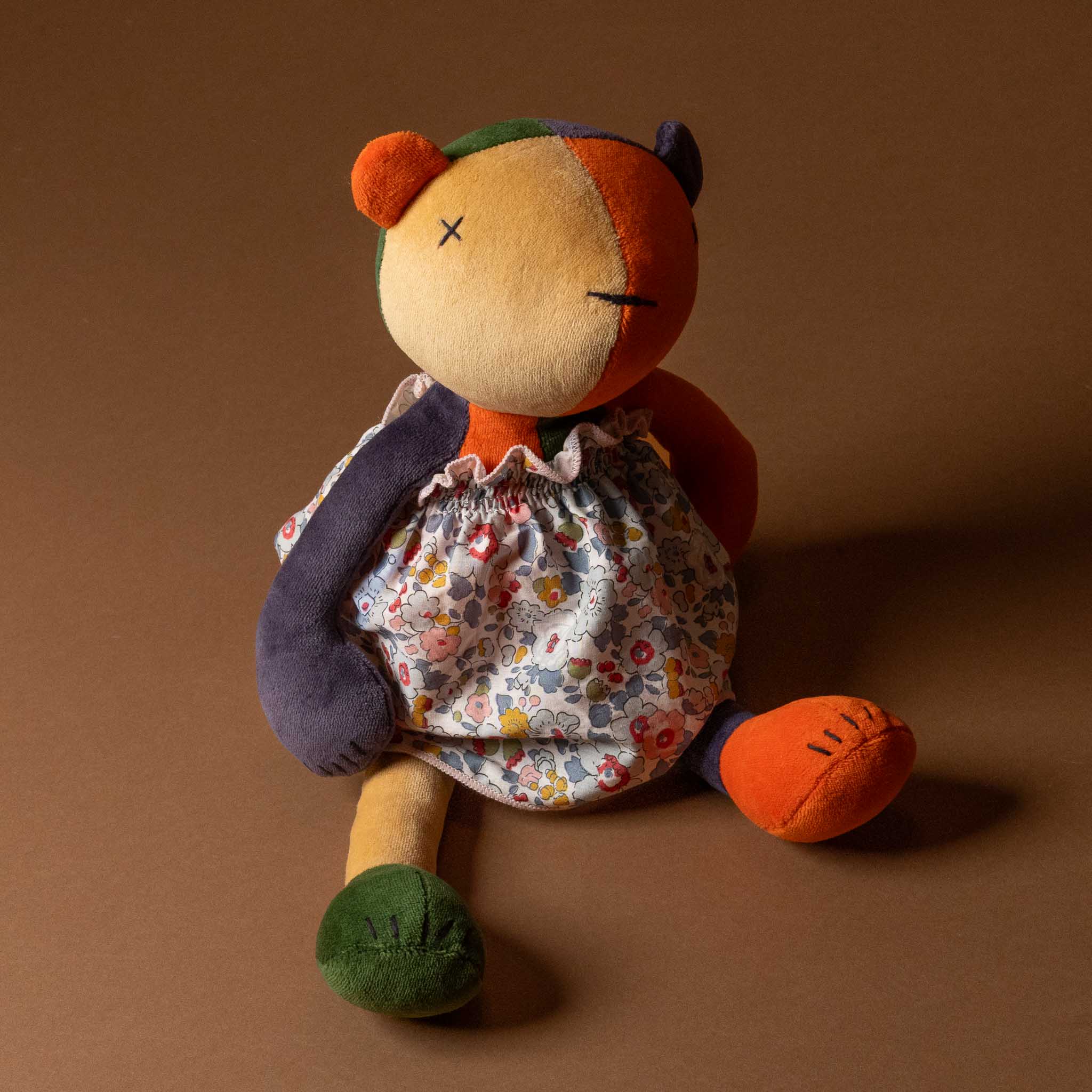 Stuffed toy bear wearing a Grande-Outfit-Liberty-Dress-Grey-_-Blue on a brown background