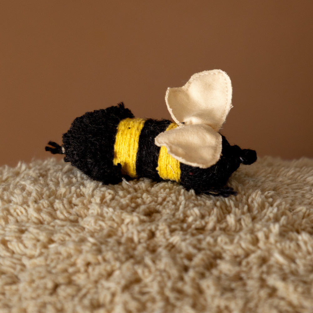 Sleepy-Bear-Floor-Cushion Toy bee with black, yellow, and white colors on a textured surface