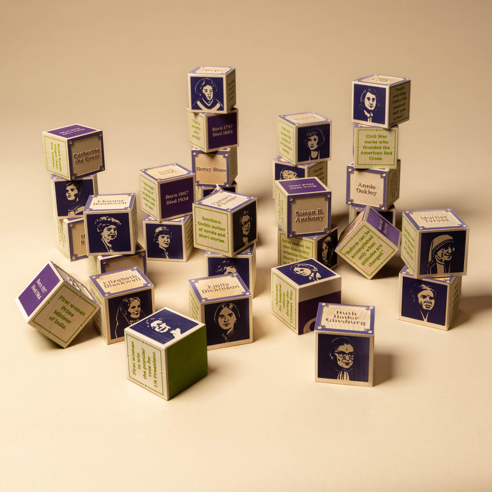 Women-Who-Dared-Wooden-Block-Set Stack of small cardboard boxes with printed faces and text on a beige background