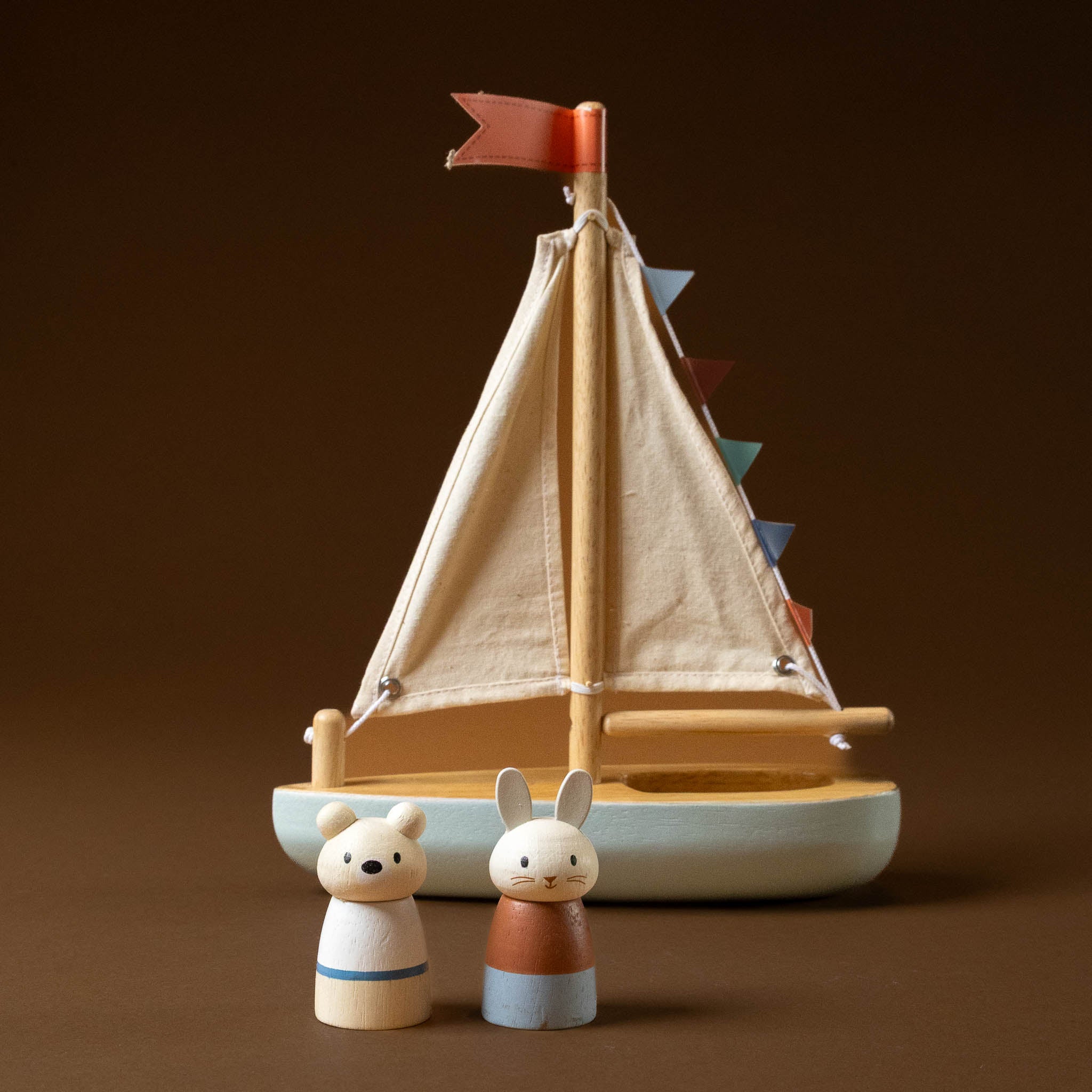 Wooden-Sailway-Boat with a red flag and two small figures on a brown background