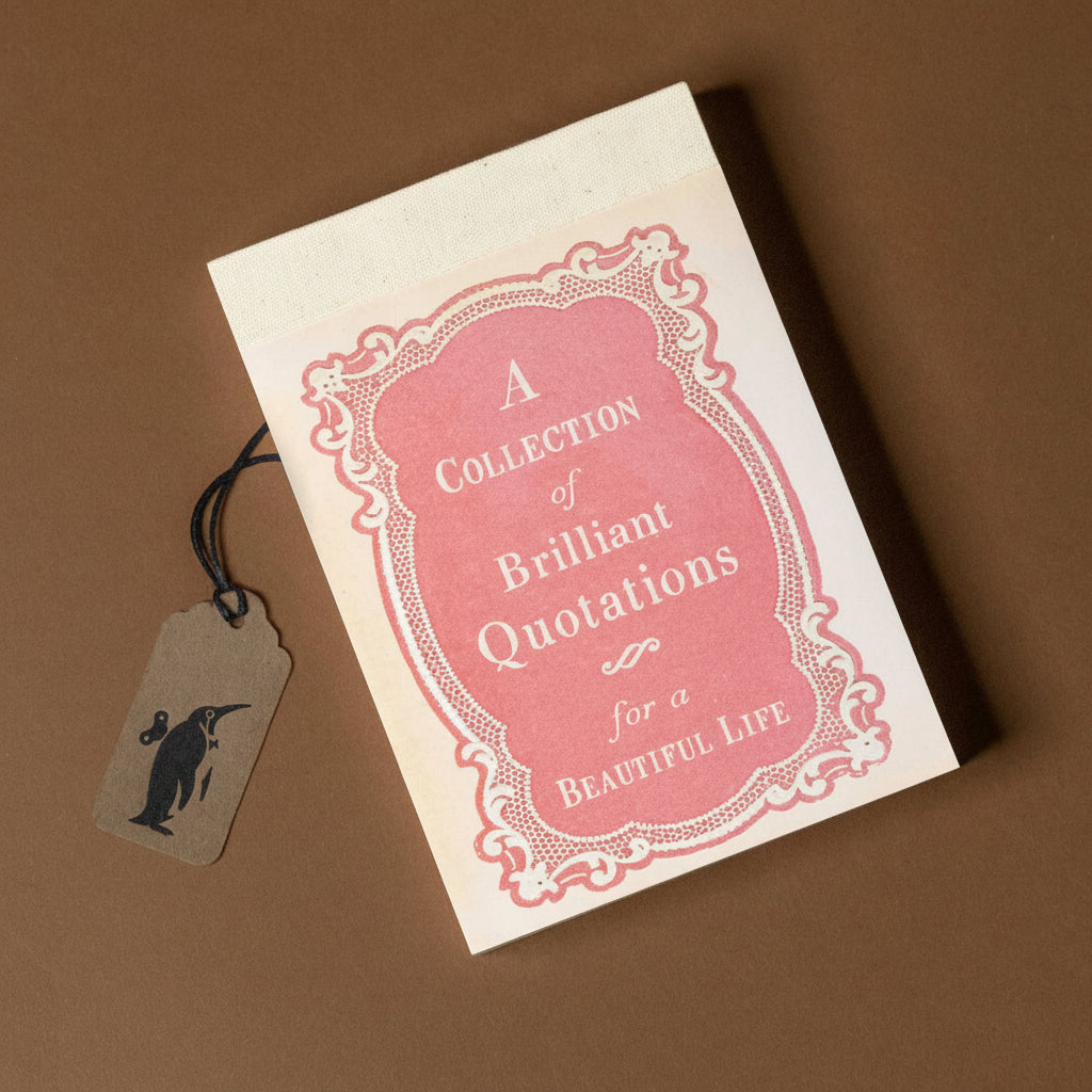 Book titled 'A Collection of Brilliant Quotations for a Beautiful Life' with a tag on a brown background