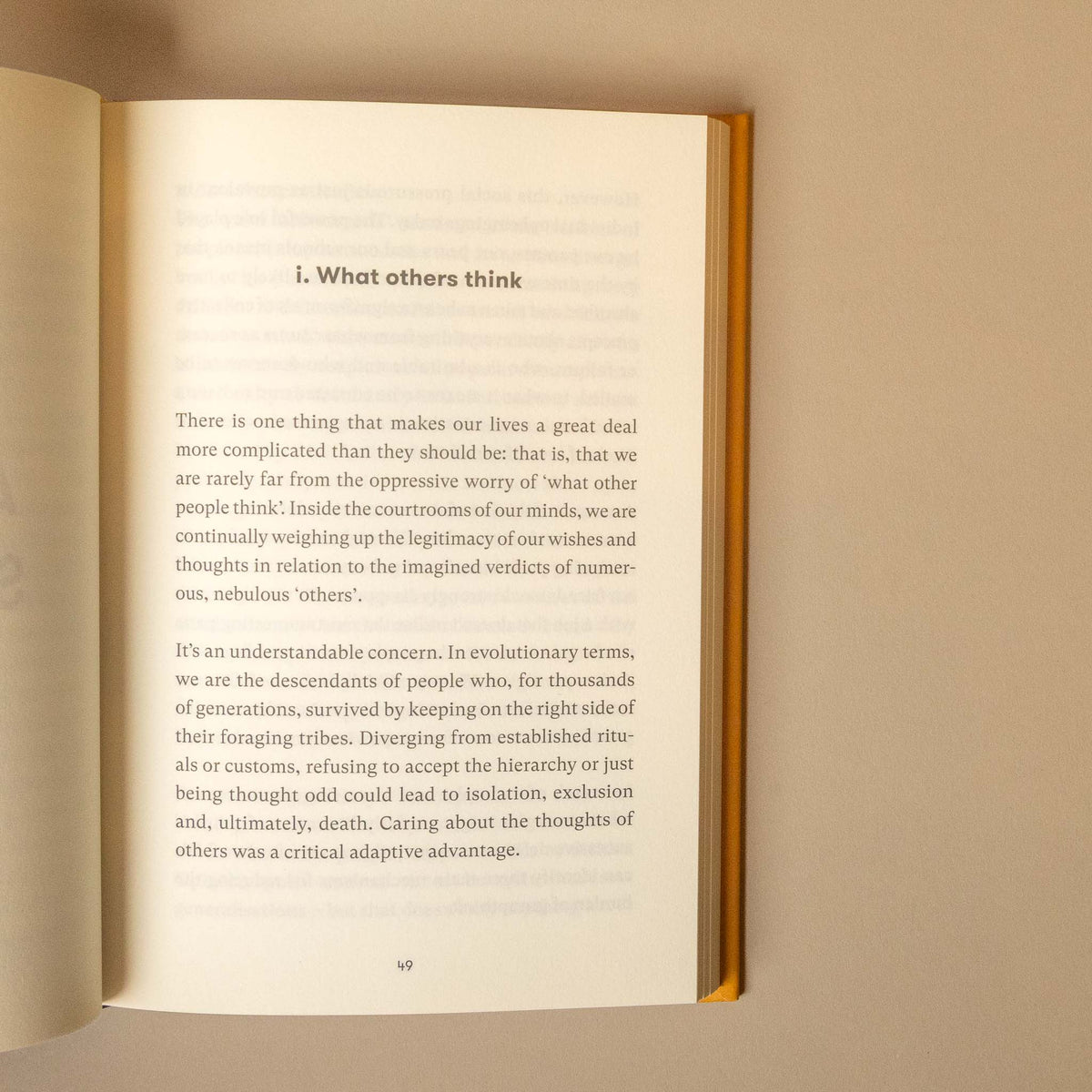 An open book showing a printed page with the heading 'i. What others think' and paragraphs of text, photographed against a plain beige background.