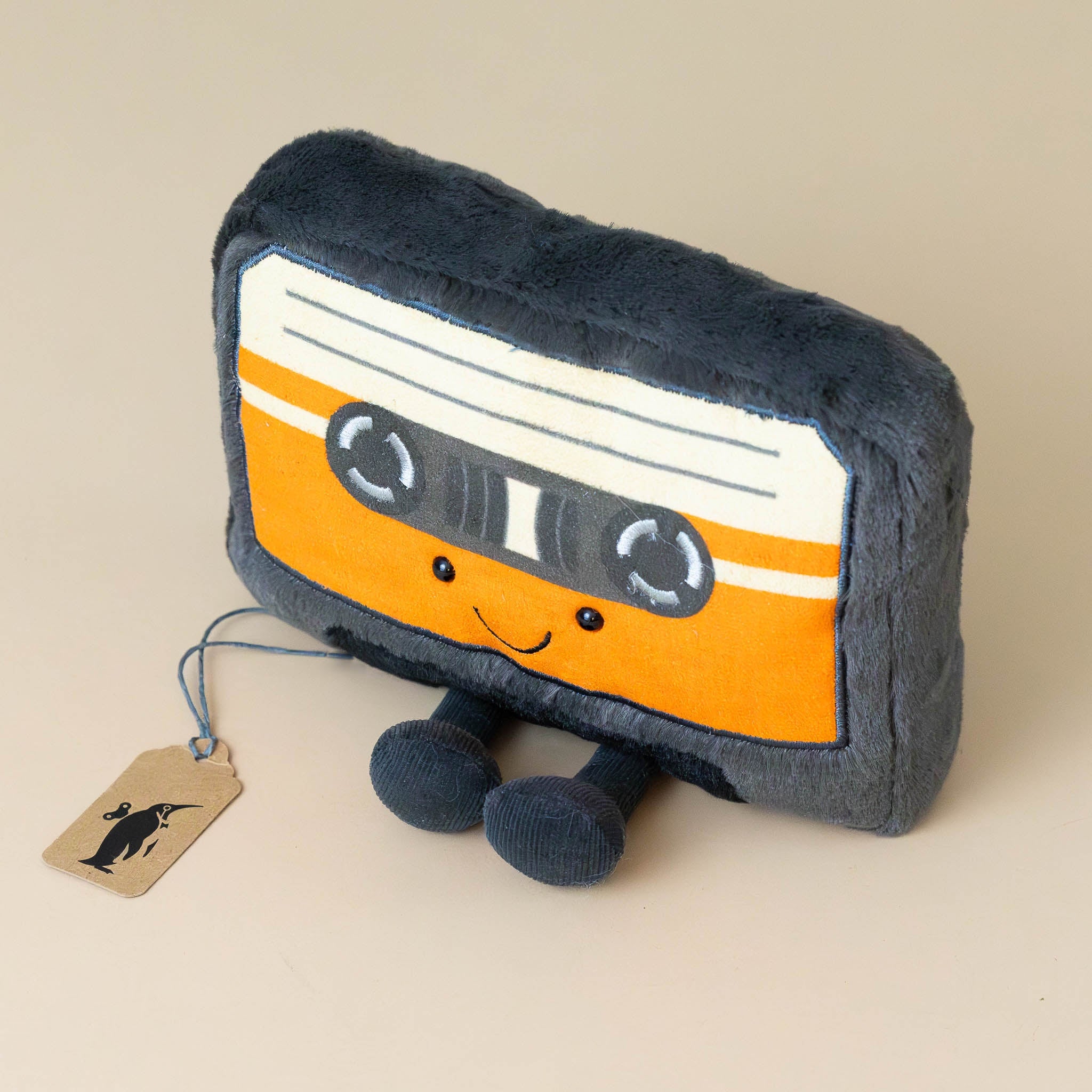 amuseable-cassette-tape-orange-and-white-label-on-black-tape-with-black-feet-stuffed-toy