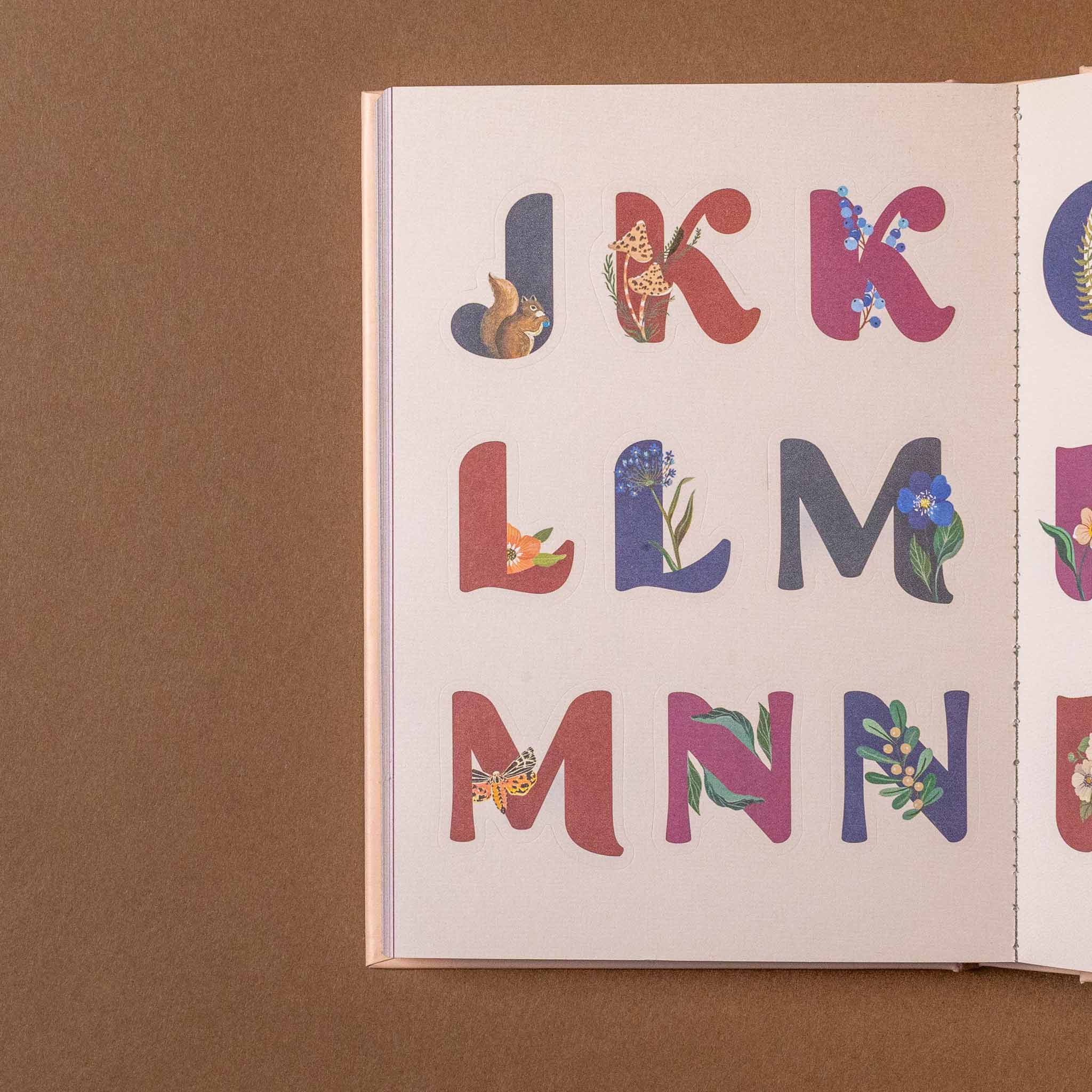 Open art-of-the-forest-100-page-sticker-book showing colorful letters on a brown background