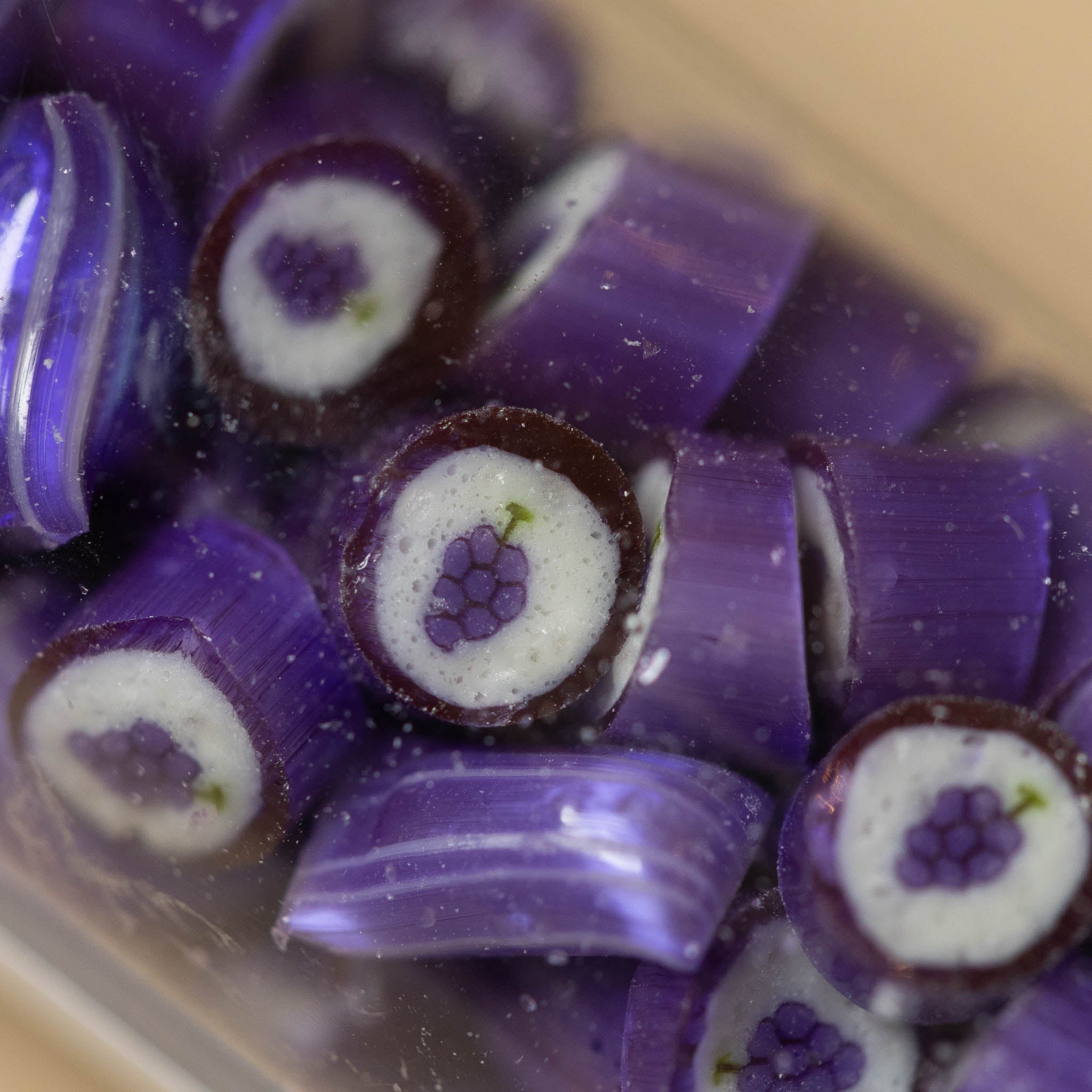 artisanal-hard-candy-tube-grape Close-up of purple and white candy pieces with a clear container.