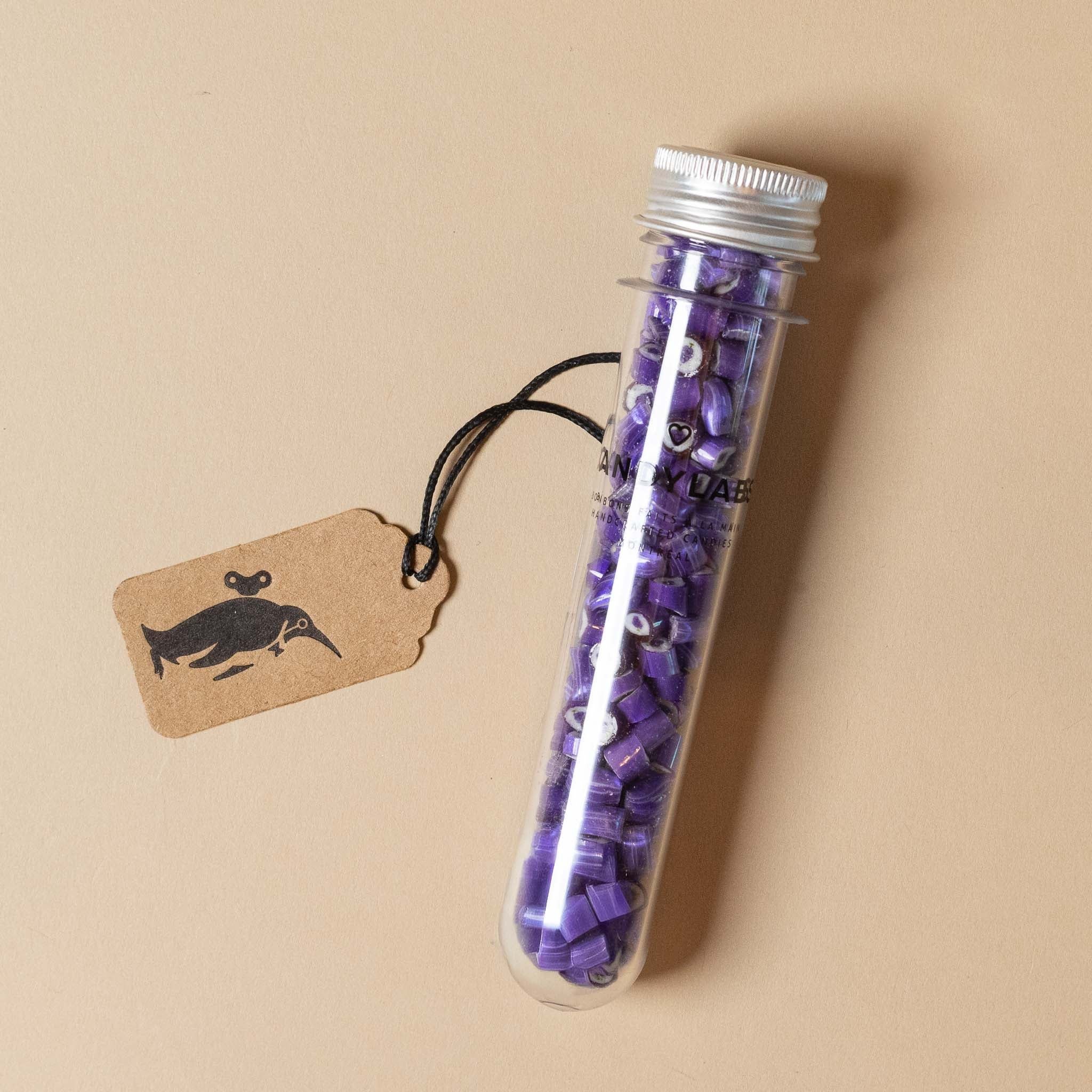 artisanal-hard-candy-tube-grape Test tube with purple candies and a tag on a beige background