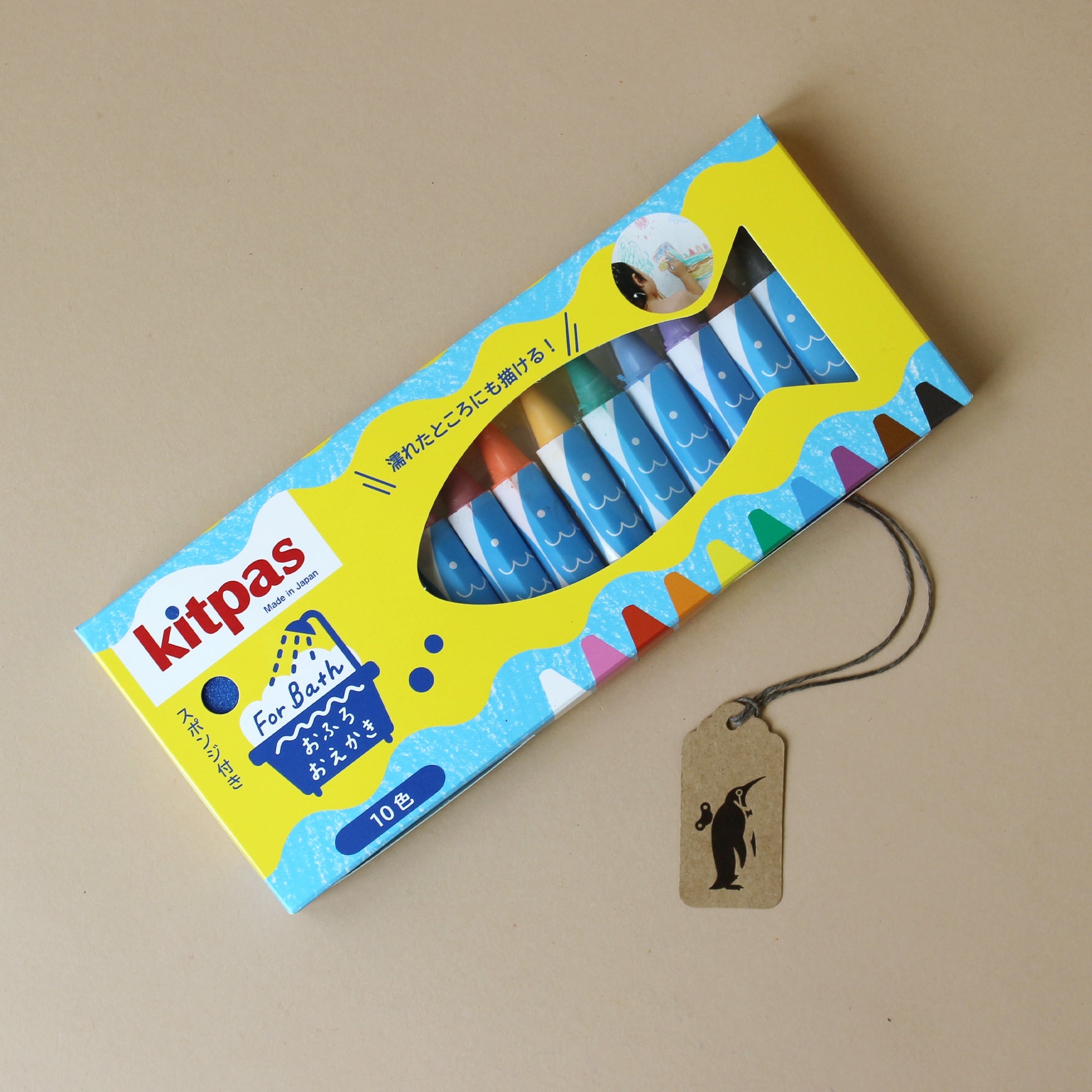 Box of bath crayons with a tag on a beige background