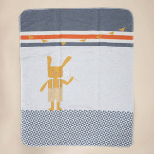 baby-blanket-embroidered-bunny-ochre-overall-shorts-holding-a-pinwheel-with-tiled-floor-and-garland-decoration