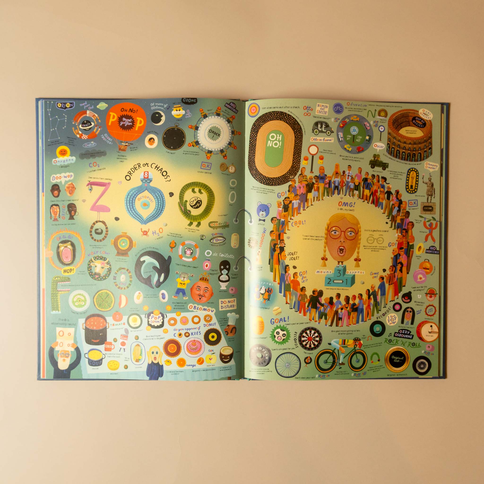 An open illustrated book or magazine spread displayed against a plain beige wall. The pages are covered in dense, colorful cartoon-style graphics, icons, and text, with a large central face illustration on the right page.