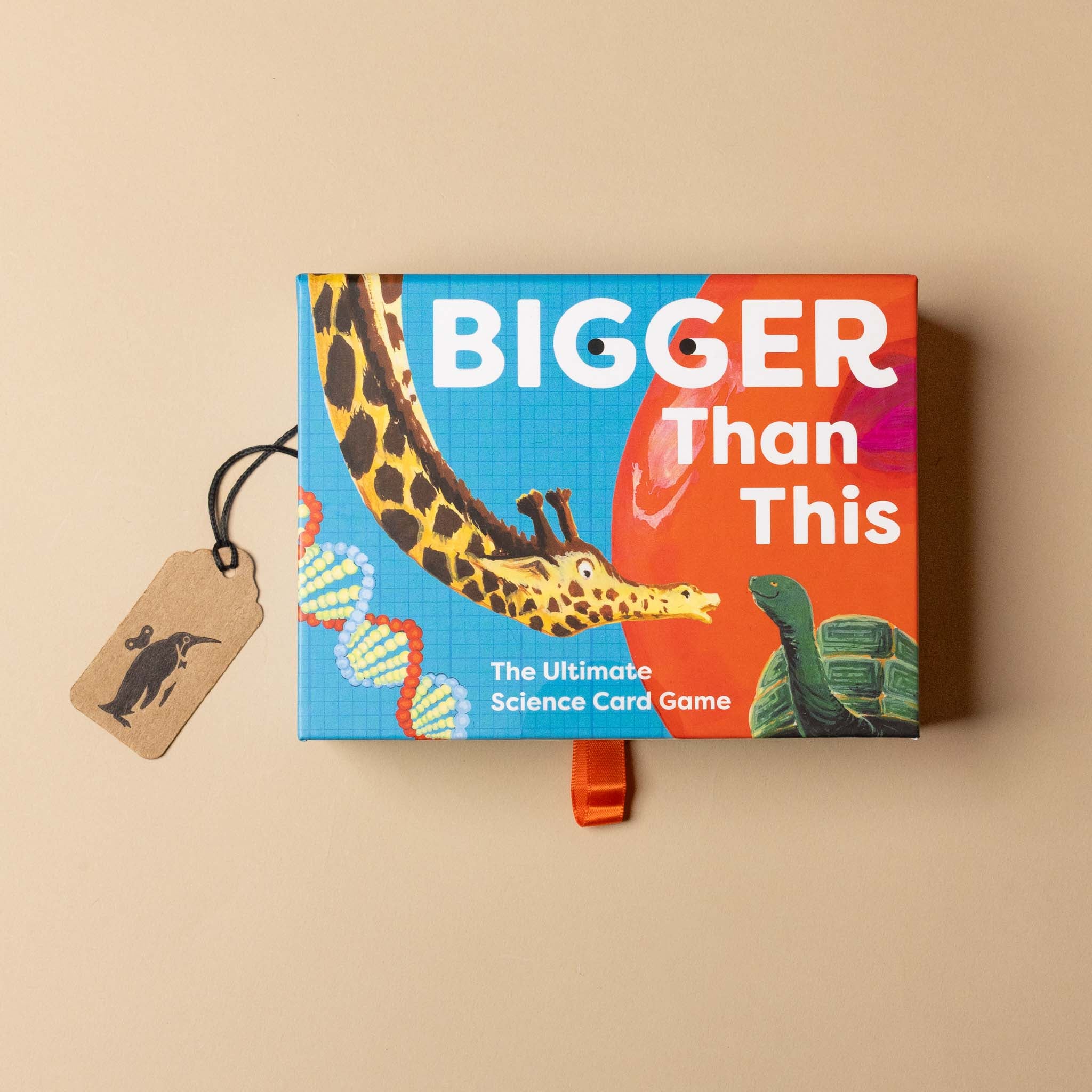 Box of 'Bigger Than This' science card game with a tag and turtle illustration on a beige background